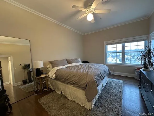 Bedroom with crown molding, dark wood finished floors, and a ceiling fan Bedroom with crown molding, dark wood finished floors, and a ceiling fan