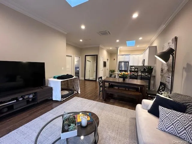 Living room with a skylight, crown molding, dark wood-type flooring, and recessed lighting Living room with a skylight, crown molding, dark wood-type flooring, and recessed lighting