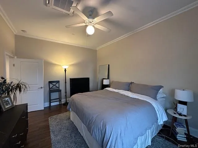 Bedroom featuring ornamental molding, ceiling fan, and dark wood-style floors Bedroom featuring ornamental molding, ceiling fan, and dark wood-style floors