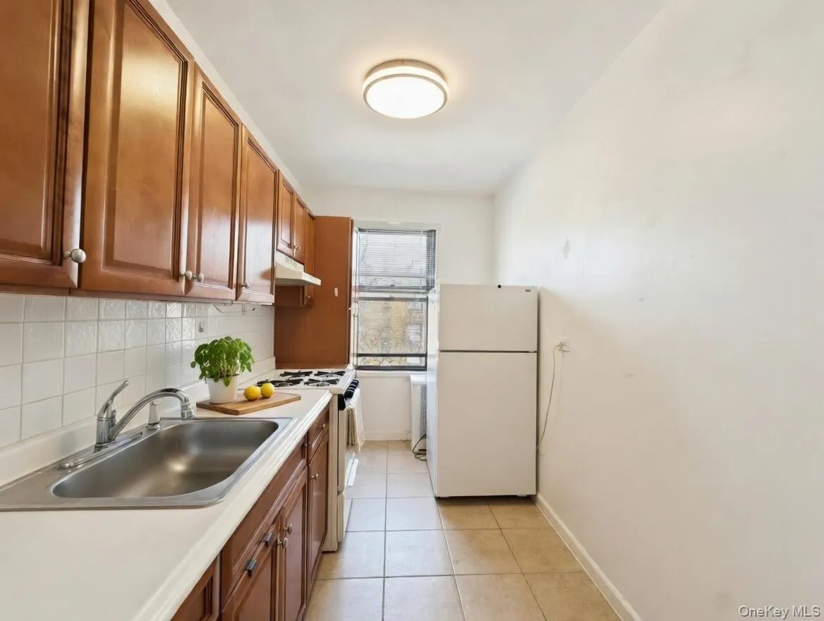 Kitchen with white appliances, light countertops, backsplash, wood finish cabinetry, and light tile patterned floors Kitchen with white appliances, light countertops, backsplash, wood finish cabinetry, and light tile patterned floors