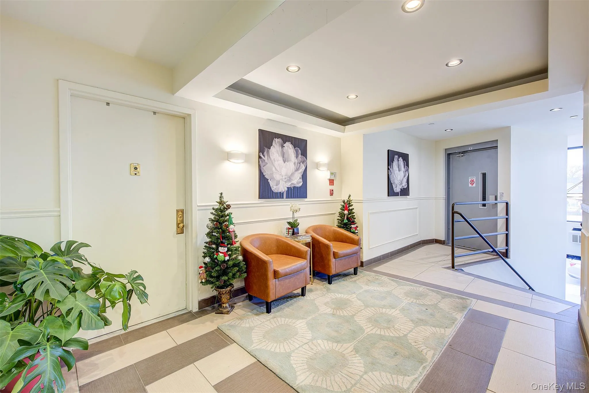 Building lobby with a raised ceiling, recessed lighting, a decorative wall, and a wainscoted wall Building lobby with a raised ceiling, recessed lighting, a decorative wall, and a wainscoted wall