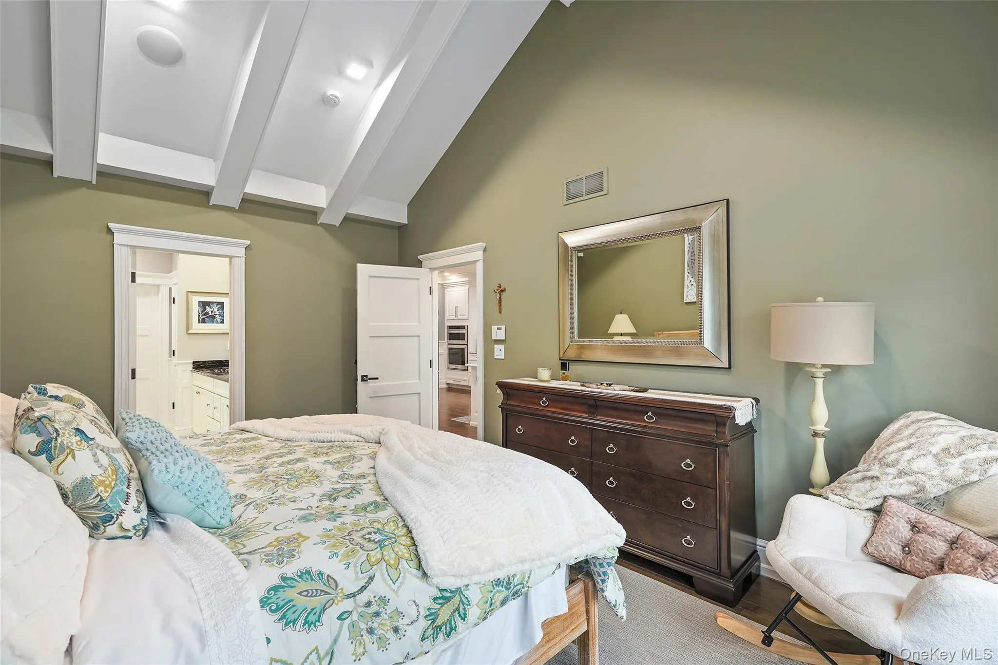 Bedroom featuring high vaulted ceiling, beam ceiling, ensuite bathroom, and wood finished floors Bedroom featuring high vaulted ceiling, beam ceiling, ensuite bathroom, and wood finished floors