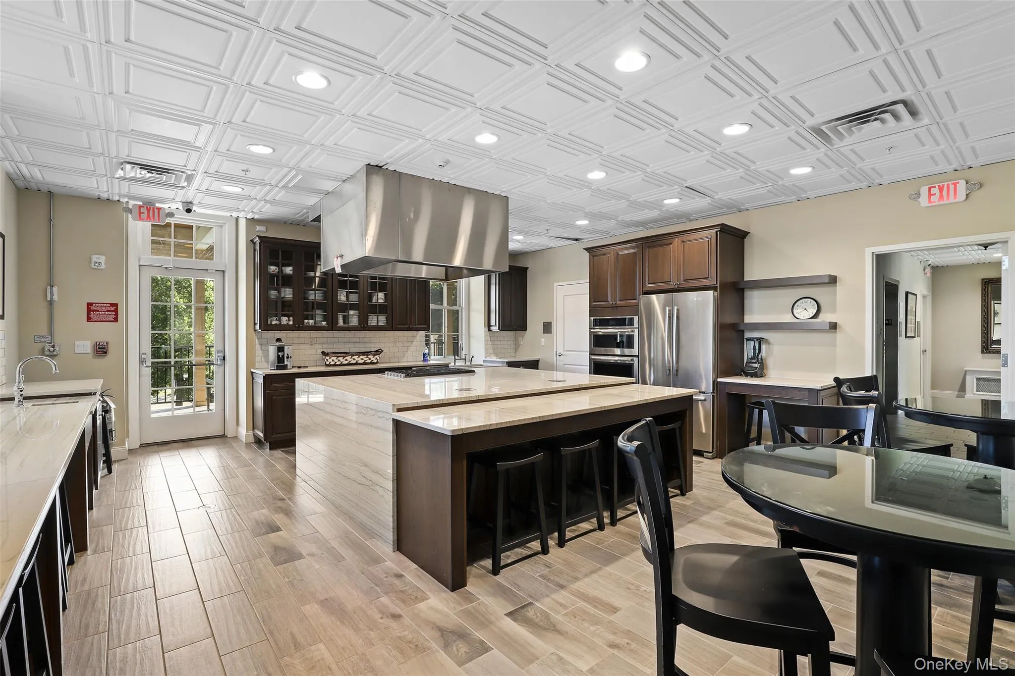 Kitchen with dark brown cabinetry, light stone countertops, an ornate ceiling, a breakfast bar area, and glass insert cabinets Kitchen with dark brown cabinetry, light stone countertops, an ornate ceiling, a breakfast bar area, and glass insert cabinets