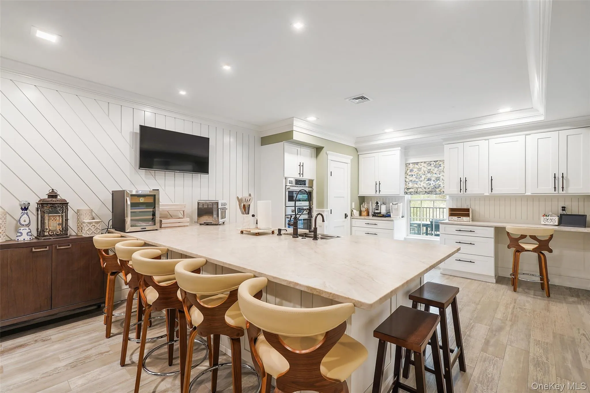 Kitchen featuring a breakfast bar area, light wood-type flooring, crown molding, recessed lighting, and wooden walls Kitchen featuring a breakfast bar area, light wood-type flooring, crown molding, recessed lighting, and wooden walls