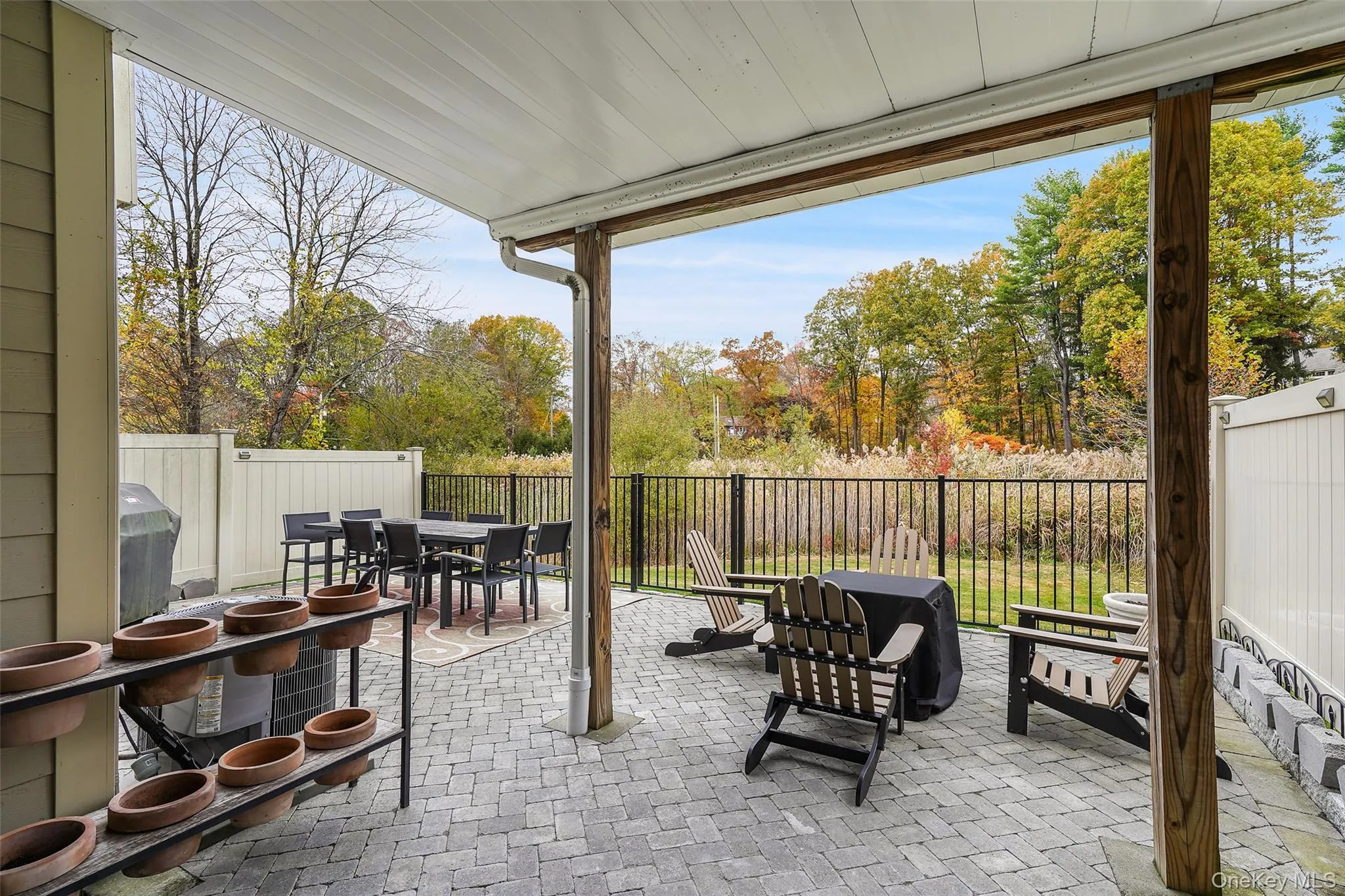 Fenced backyard featuring outdoor dining space, a patio, and view of scattered trees Fenced backyard featuring outdoor dining space, a patio, and view of scattered trees