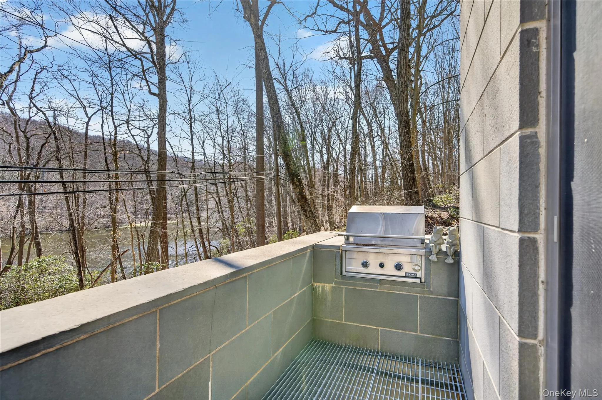 Outdoor cooking area featuring an integrated stainless steel grill and stone-tiled walls Outdoor cooking area featuring an integrated stainless steel grill and stone-tiled walls