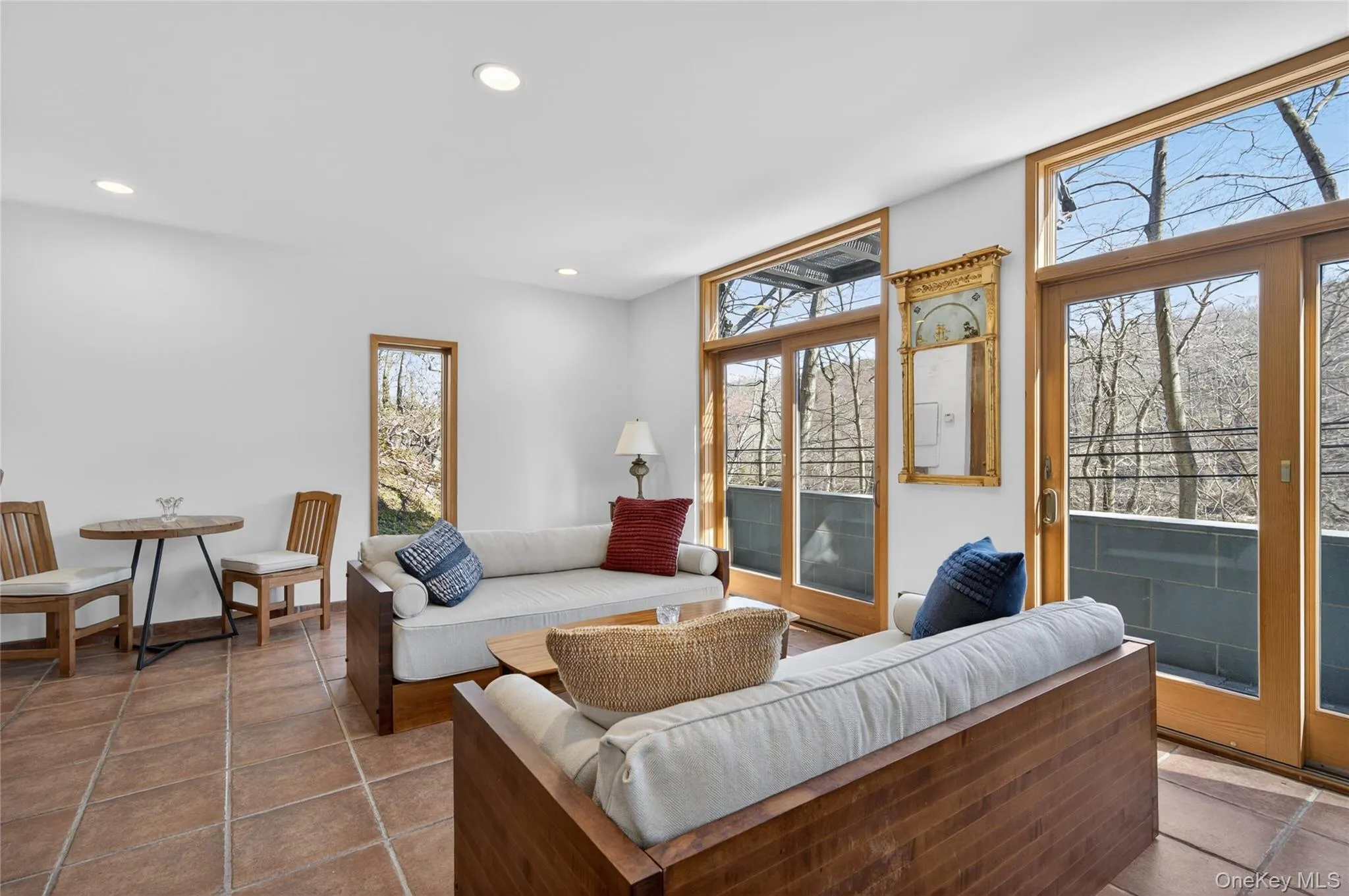 Bright living space featuring large sliding glass doors, a single fixed window, recessed lighting, and tile flooring Bright living space featuring large sliding glass doors, a single fixed window, recessed lighting, and tile flooring