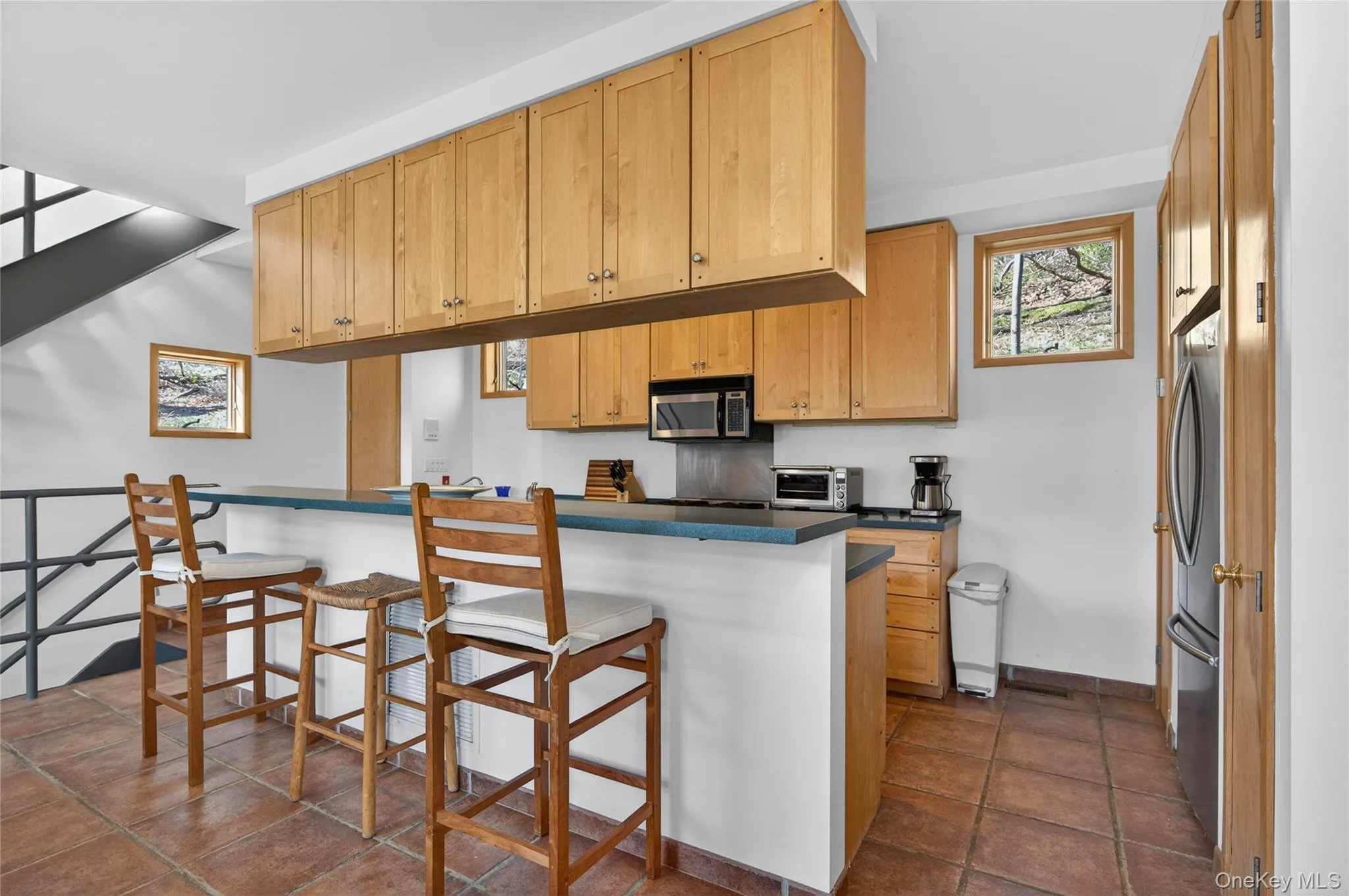 Kitchen area featuring light wood cabinetry, a breakfast bar with countertop, and tile flooring Kitchen area featuring light wood cabinetry, a breakfast bar with countertop, and tile flooring