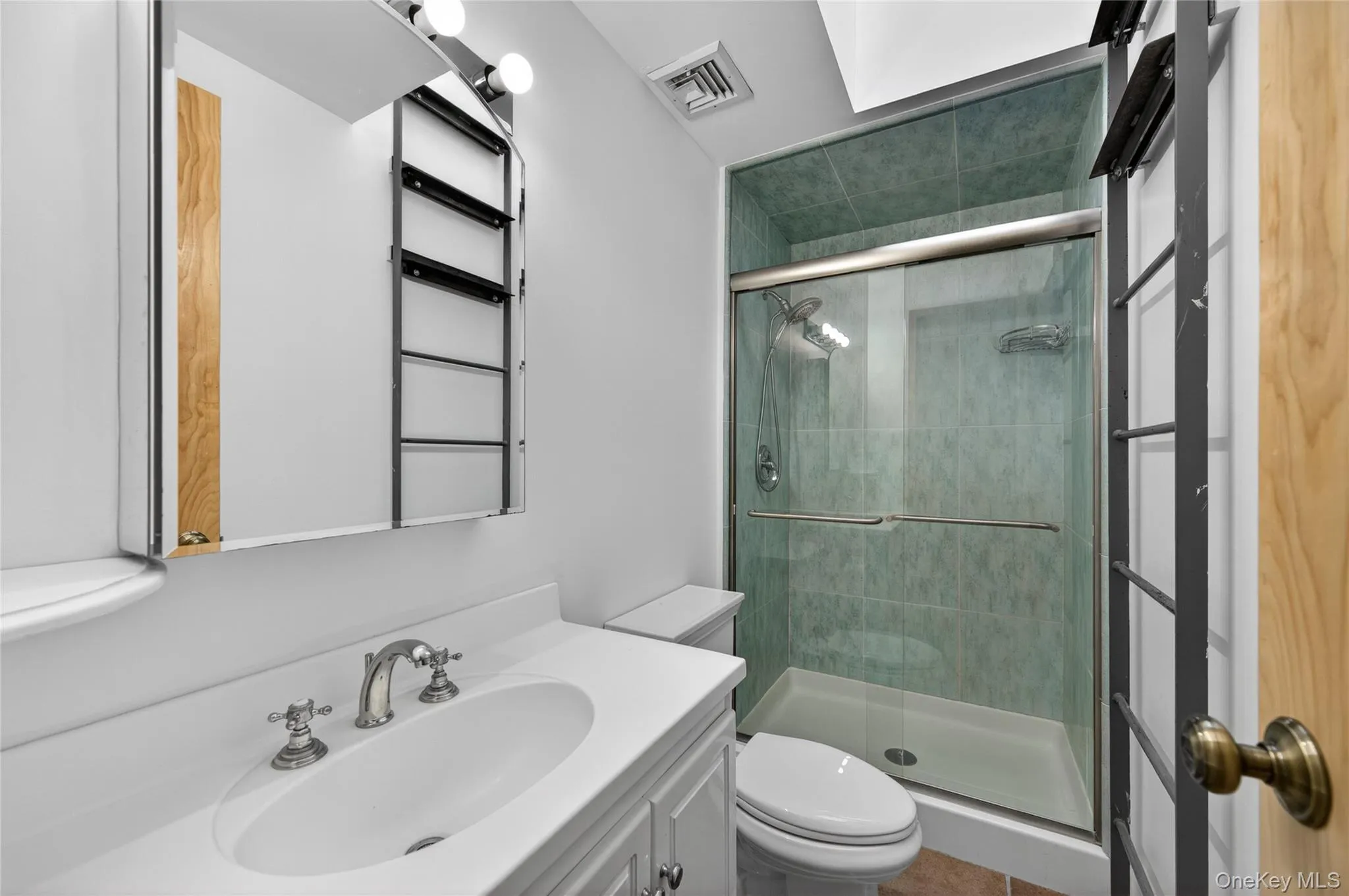 Bathroom featuring a white vanity with an integrated sink, polished chrome faucet, and mirrored medicine cabinet with exposed shelving Bathroom featuring a white vanity with an integrated sink, polished chrome faucet, and mirrored medicine cabinet with exposed shelving