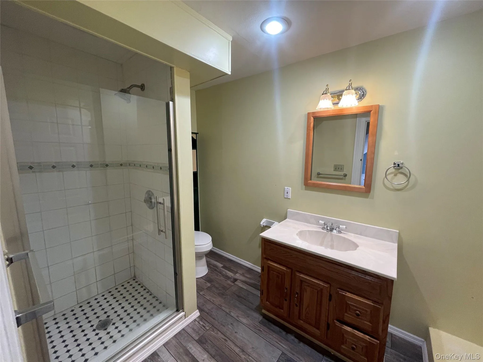 Bathroom with a shower stall, vanity, wood finished floors, and recessed lighting Bathroom with a shower stall, vanity, wood finished floors, and recessed lighting