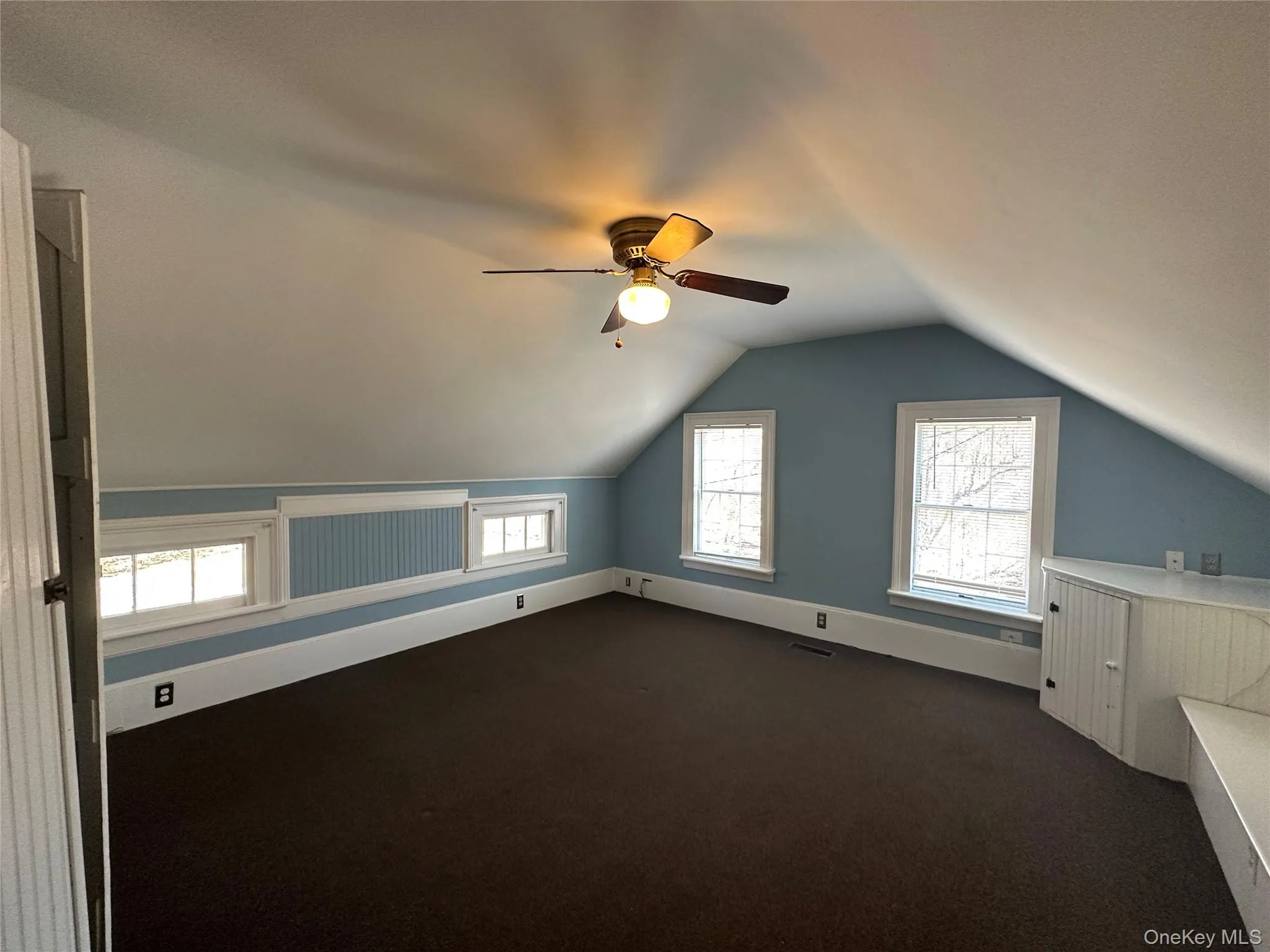 Bonus room featuring lofted ceiling, a ceiling fan, and dark carpet Bonus room featuring lofted ceiling, a ceiling fan, and dark carpet