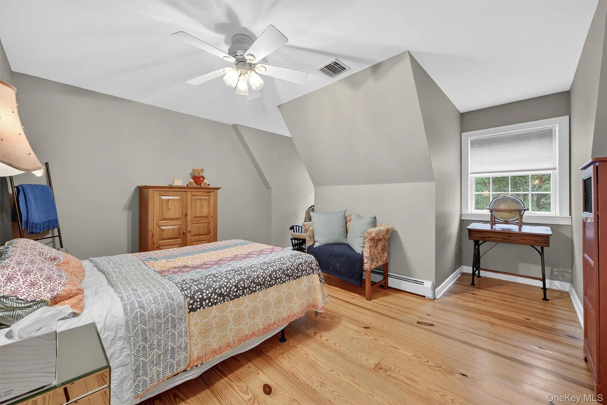 Bedroom featuring baseboard heating, wood finished floors, and a ceiling fan Bedroom featuring baseboard heating, wood finished floors, and a ceiling fan