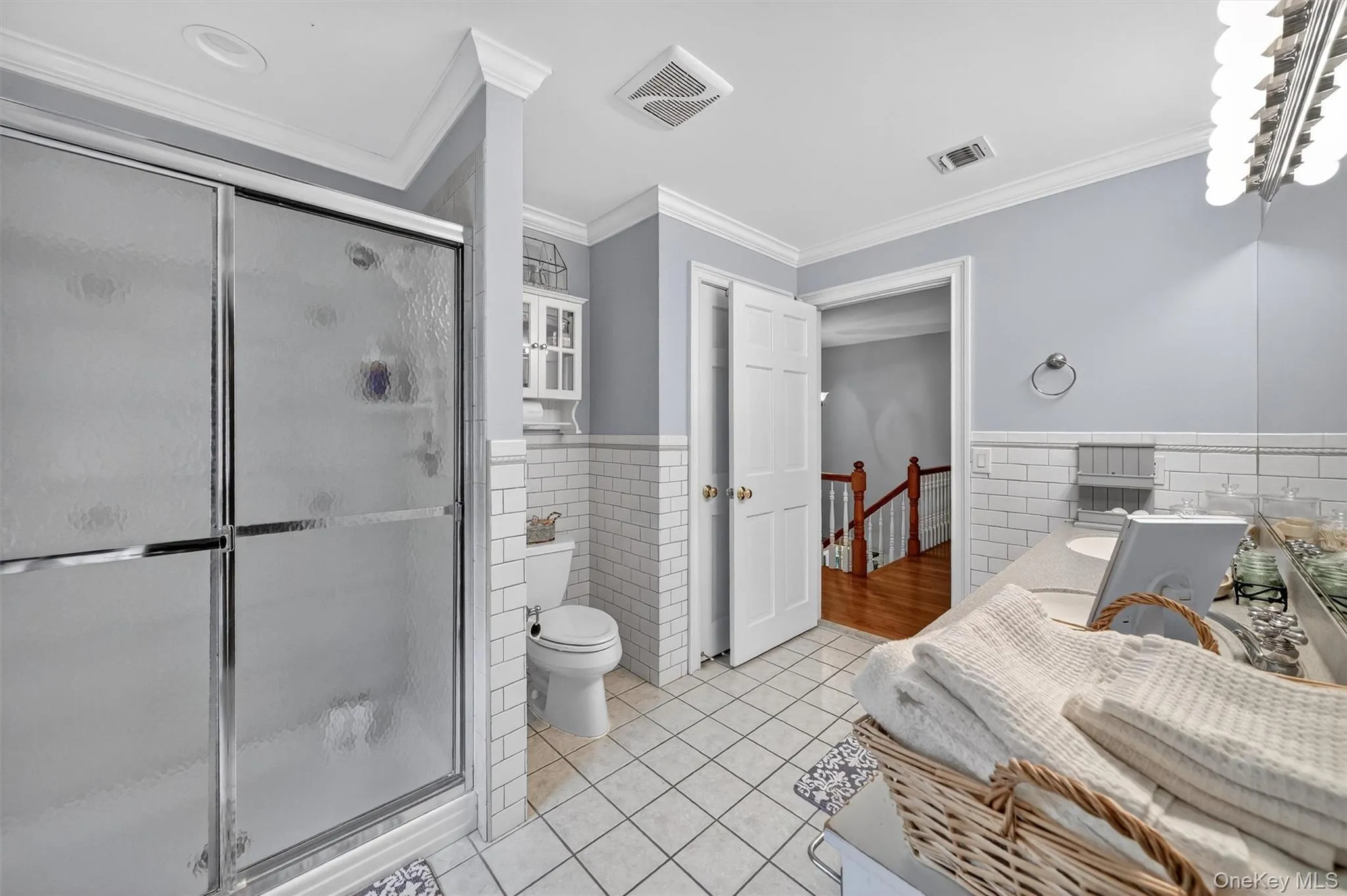Bathroom with tile walls, tile patterned floors, wainscoting, vanity, and a stall shower Bathroom with tile walls, tile patterned floors, wainscoting, vanity, and a stall shower