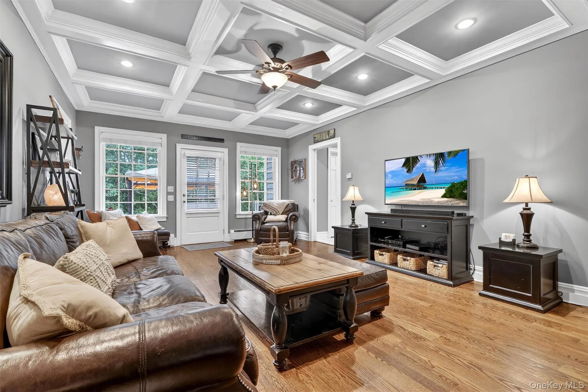 Living area with light wood-style flooring, a ceiling fan, a baseboard heating unit, coffered ceiling, and beamed ceiling Living area with light wood-style flooring, a ceiling fan, a baseboard heating unit, coffered ceiling, and beamed ceiling