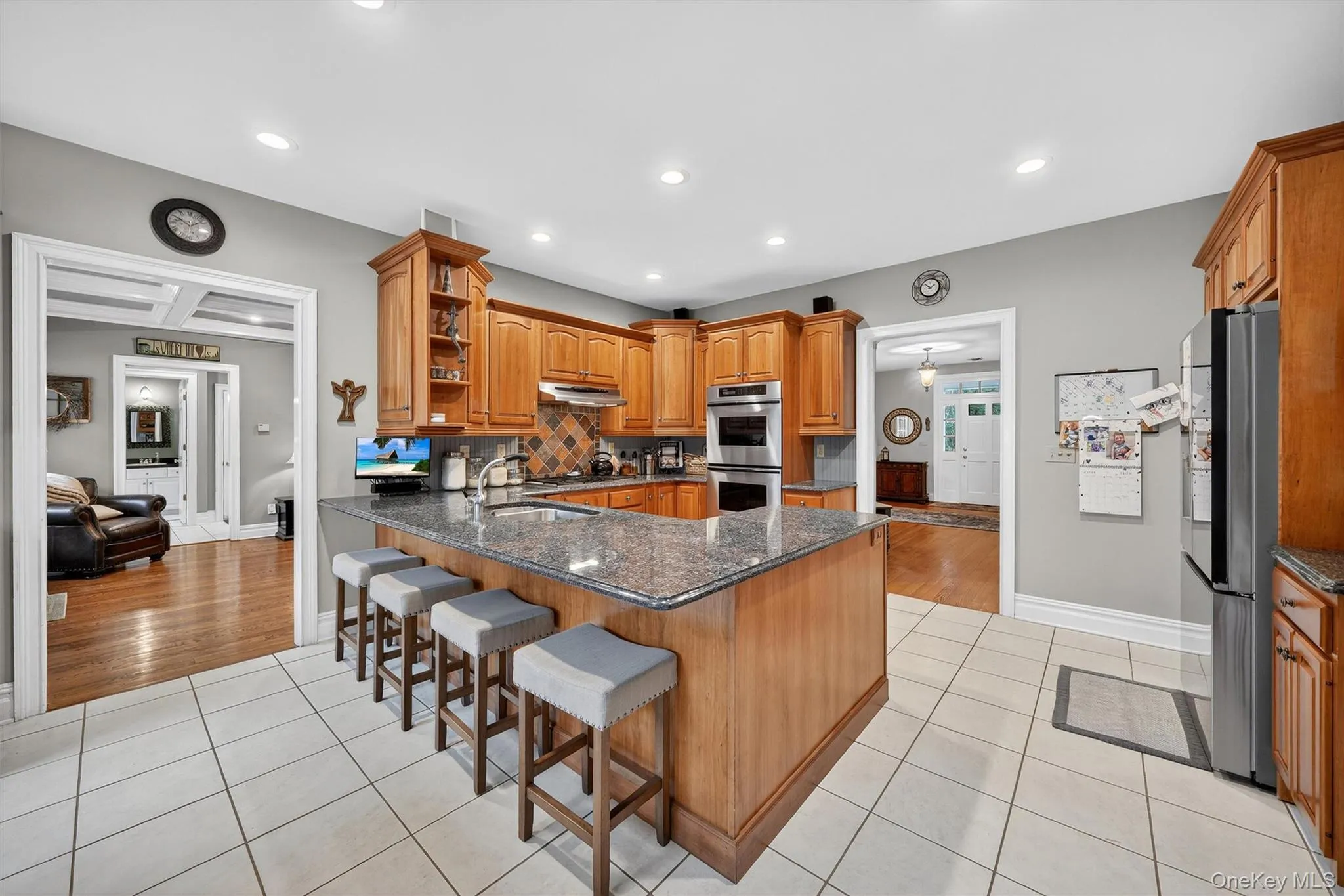 Kitchen featuring appliances with stainless steel finishes, under cabinet range hood, light tile patterned flooring, open shelves, and a peninsula Kitchen featuring appliances with stainless steel finishes, under cabinet range hood, light tile patterned flooring, open shelves, and a peninsula