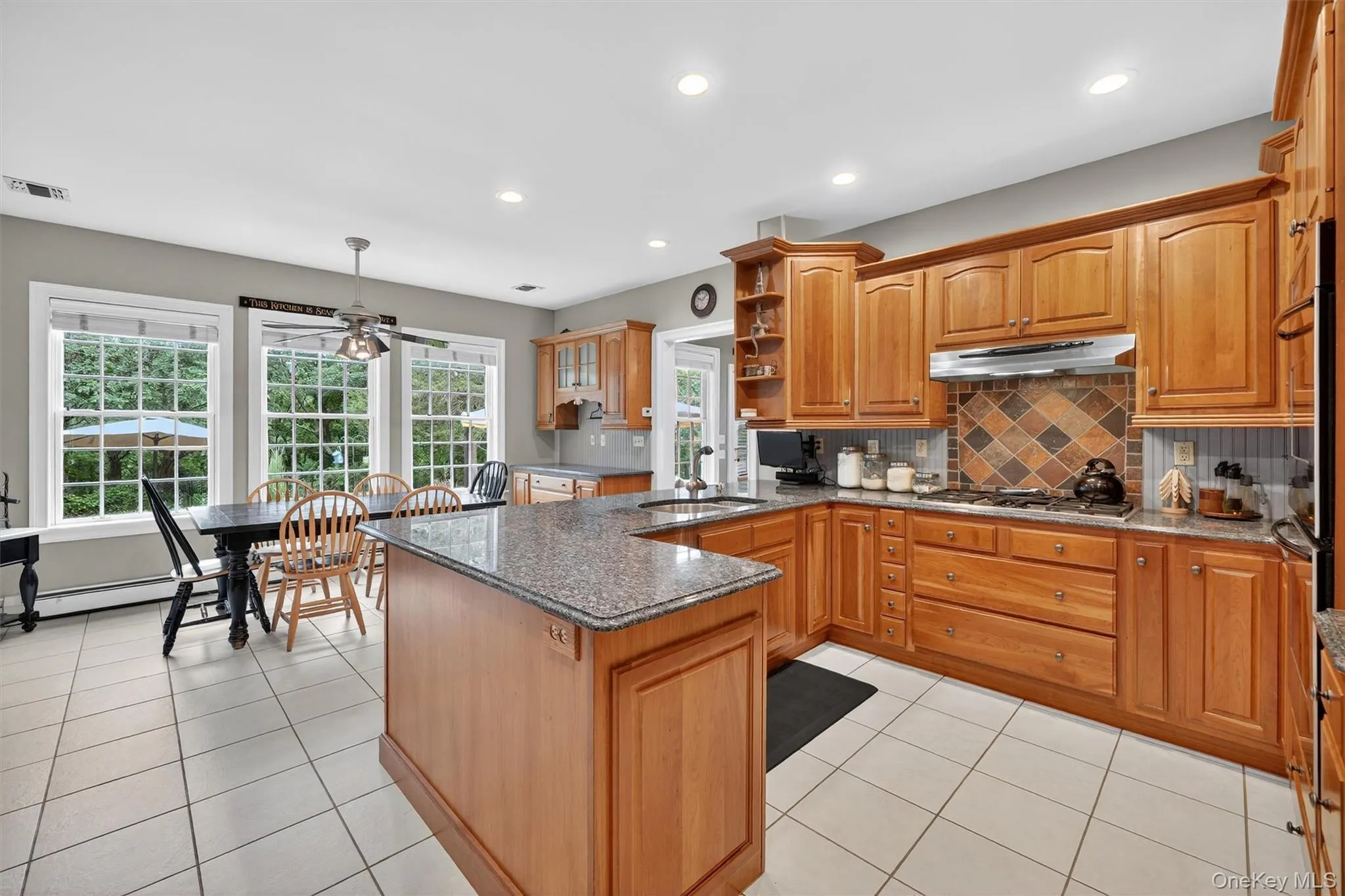 Kitchen with under cabinet range hood, stainless steel gas cooktop, ceiling fan, light tile patterned flooring, and recessed lighting Kitchen with under cabinet range hood, stainless steel gas cooktop, ceiling fan, light tile patterned flooring, and recessed lighting