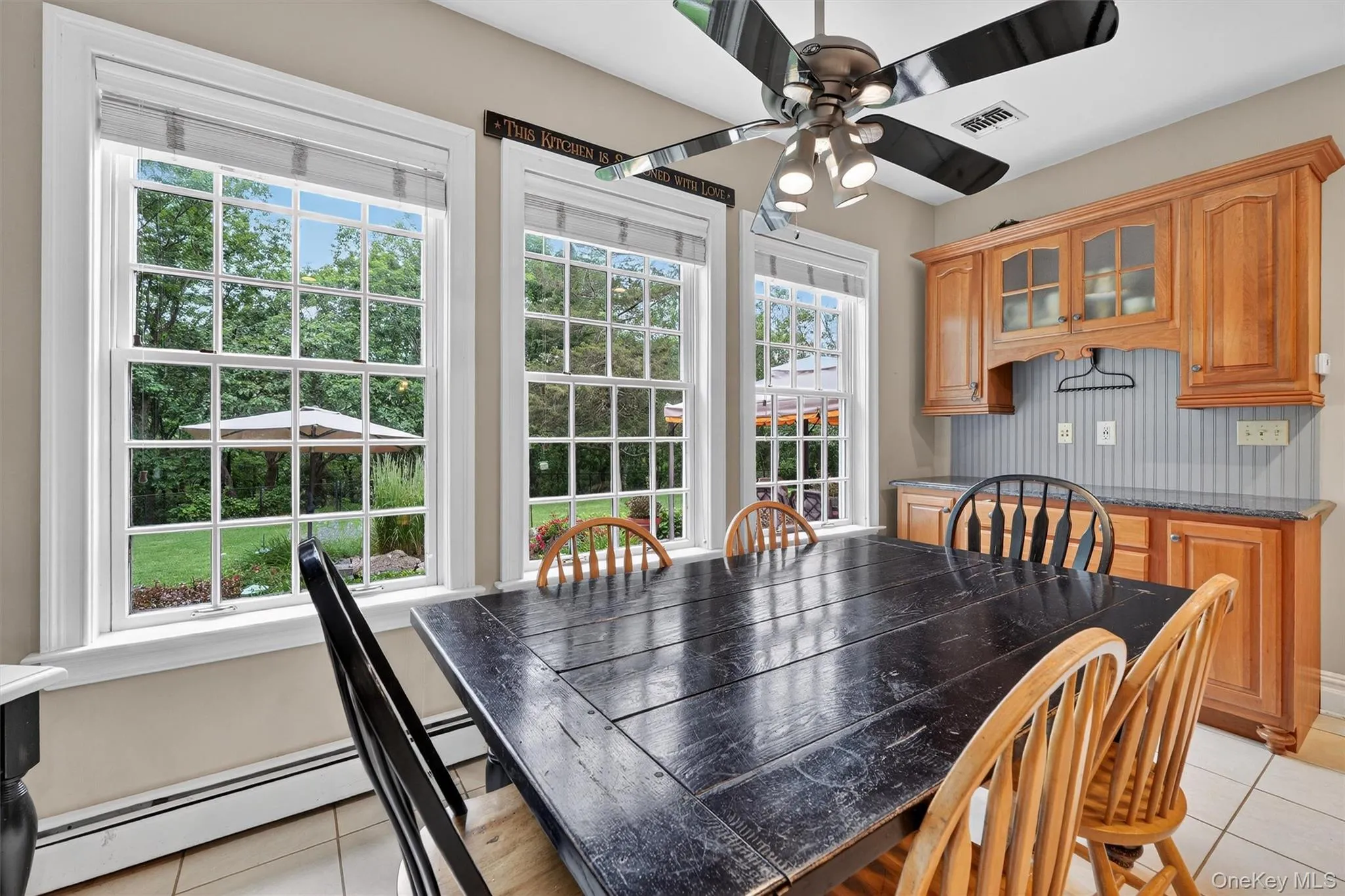 Dining room with light tile patterned floors, ceiling fan, plenty of natural light, and baseboard heating Dining room with light tile patterned floors, ceiling fan, plenty of natural light, and baseboard heating