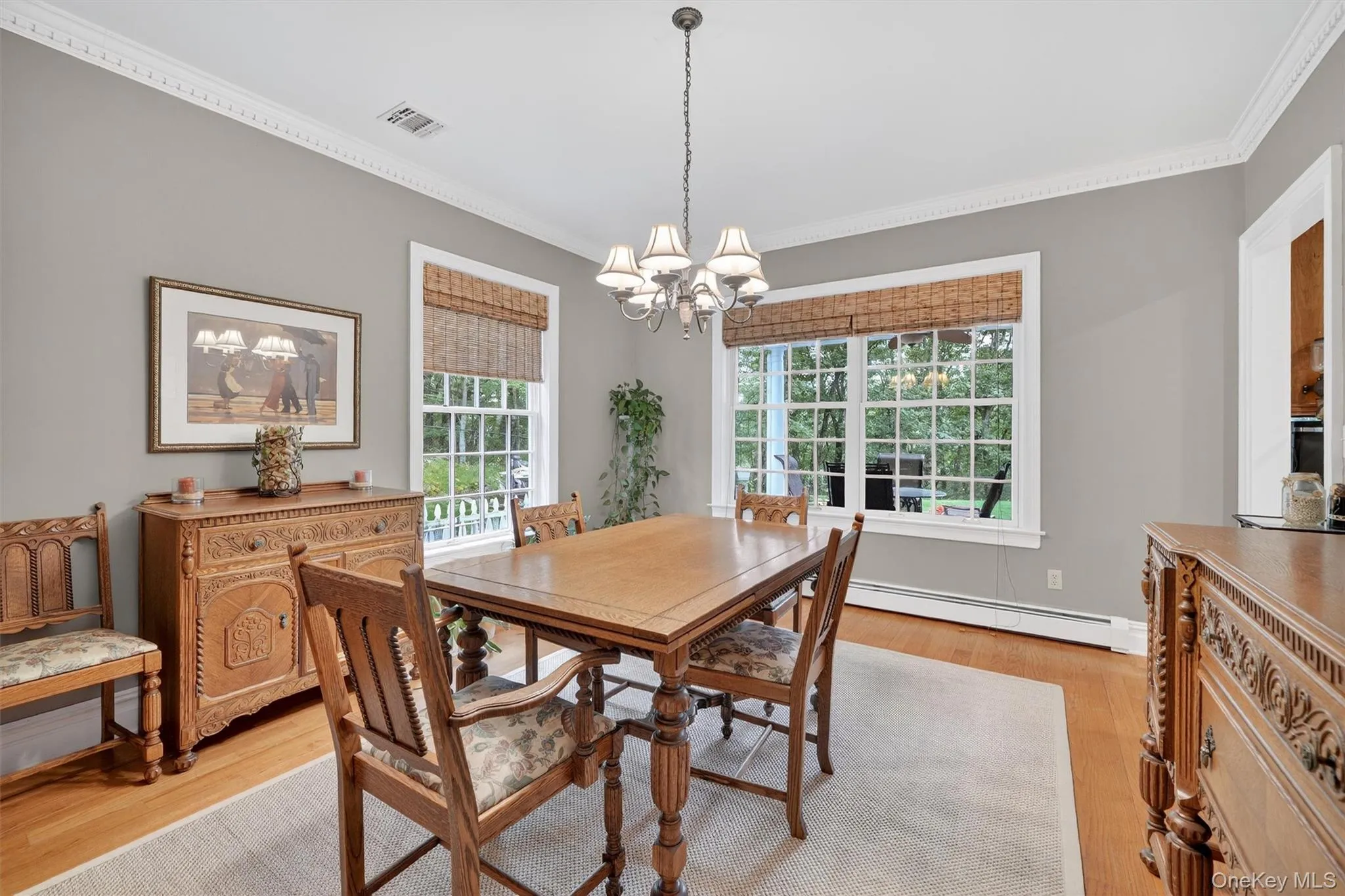 Dining space with a chandelier, ornamental molding, light wood-style flooring, and a baseboard heating unit Dining space with a chandelier, ornamental molding, light wood-style flooring, and a baseboard heating unit