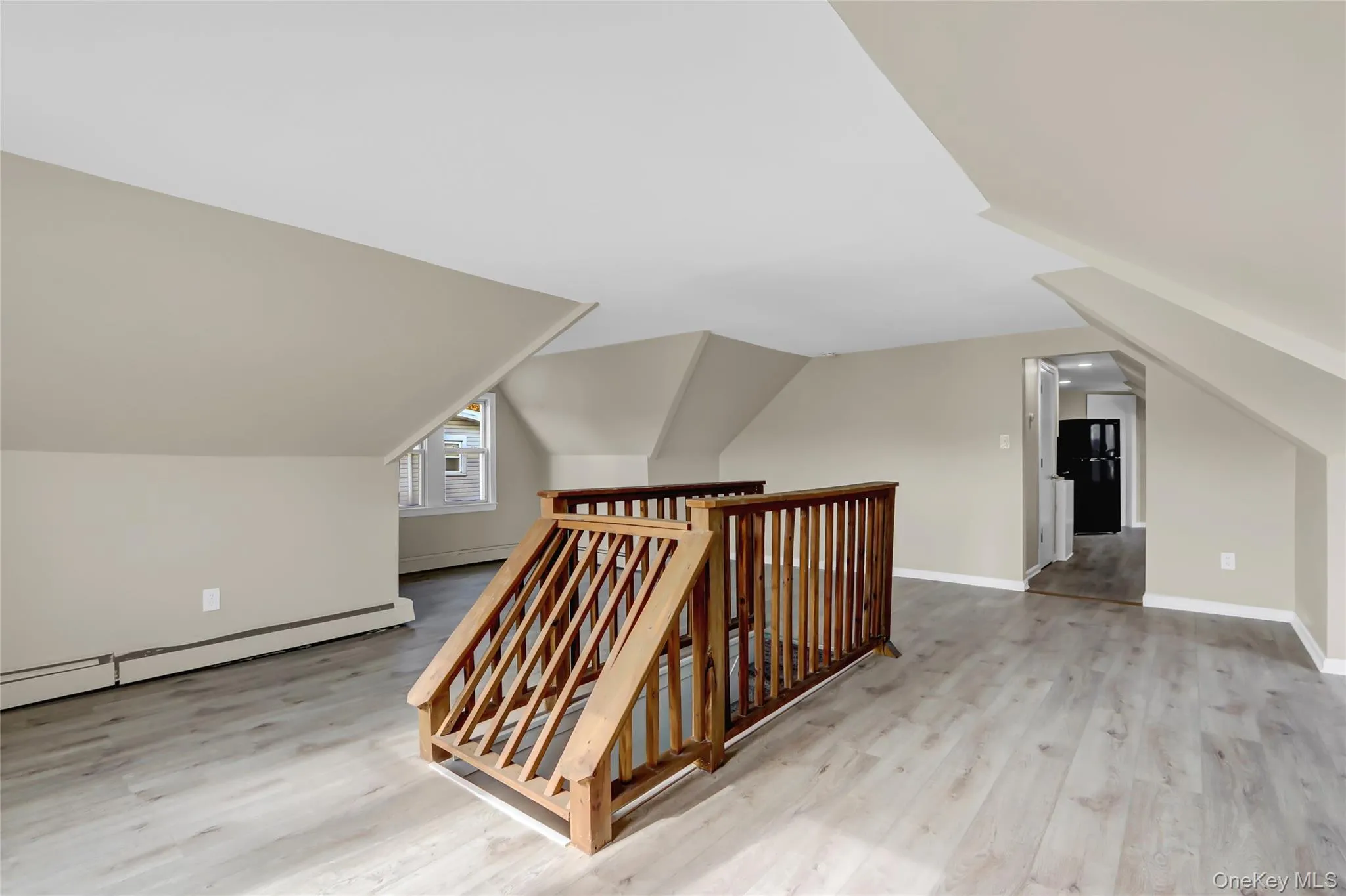 Additional living space with lofted ceiling, baseboards, and wood finished floors Additional living space with lofted ceiling, baseboards, and wood finished floors