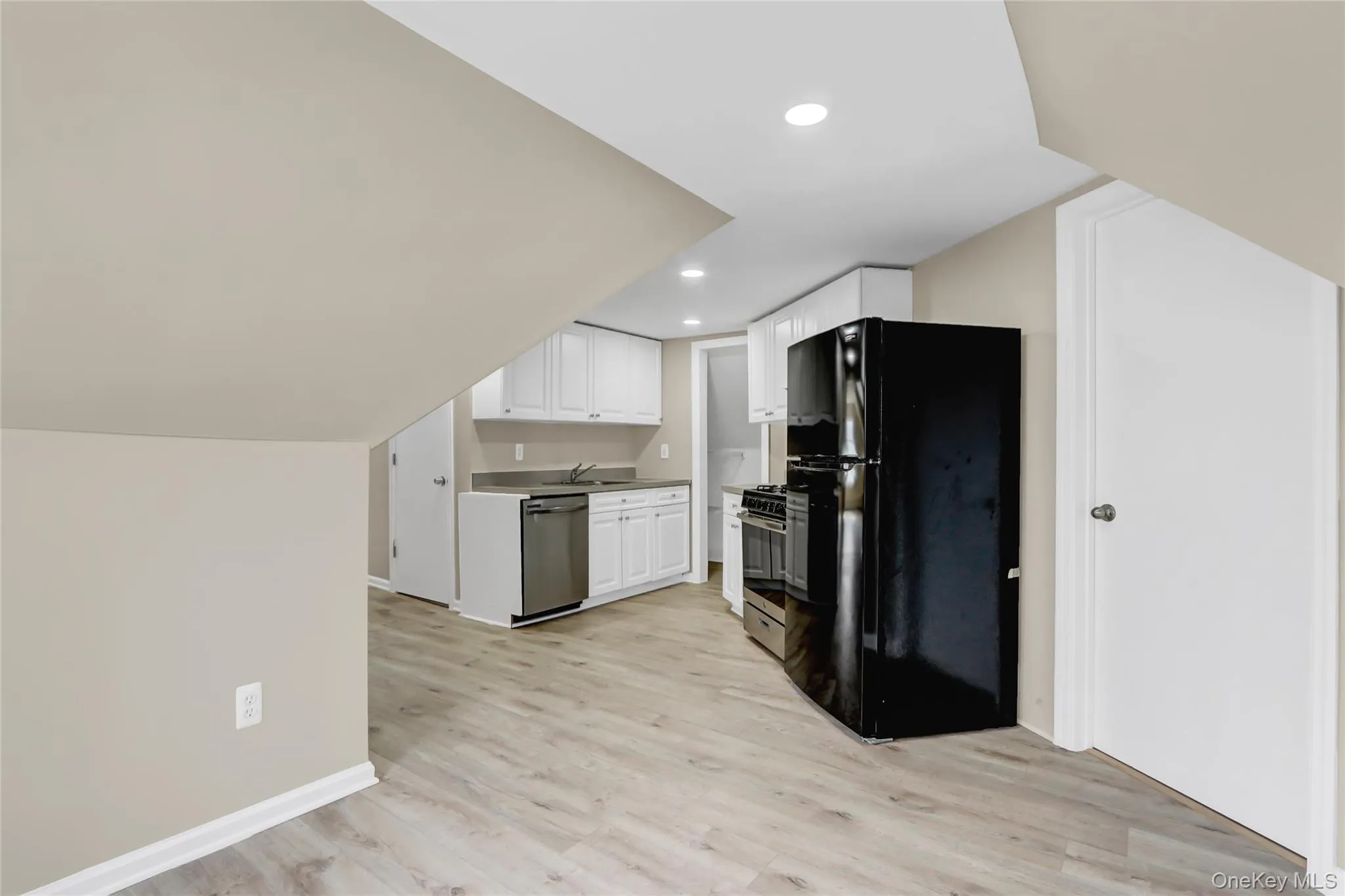 Kitchen featuring white cabinetry, recessed lighting, light wood-style floors, appliances with stainless steel finishes, and lofted ceiling Kitchen featuring white cabinetry, recessed lighting, light wood-style floors, appliances with stainless steel finishes, and lofted ceiling