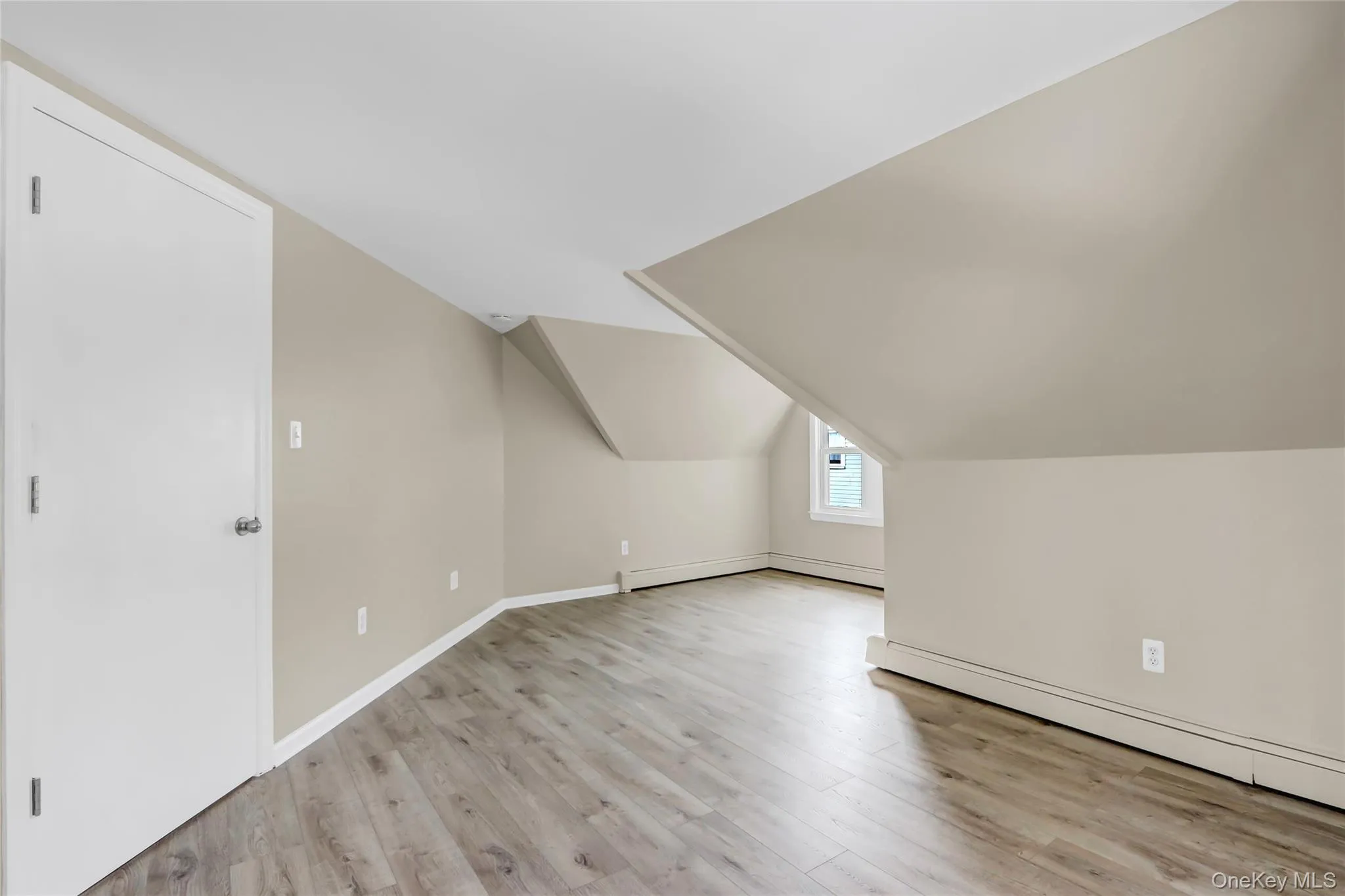 Additional living space featuring a baseboard heating unit, lofted ceiling, light wood-style flooring, and baseboards Additional living space featuring a baseboard heating unit, lofted ceiling, light wood-style flooring, and baseboards