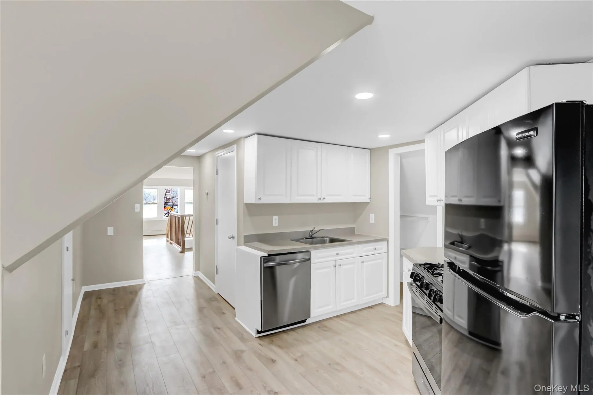 Kitchen featuring freestanding refrigerator, a sink, light countertops, stainless steel dishwasher, and gas range Kitchen featuring freestanding refrigerator, a sink, light countertops, stainless steel dishwasher, and gas range