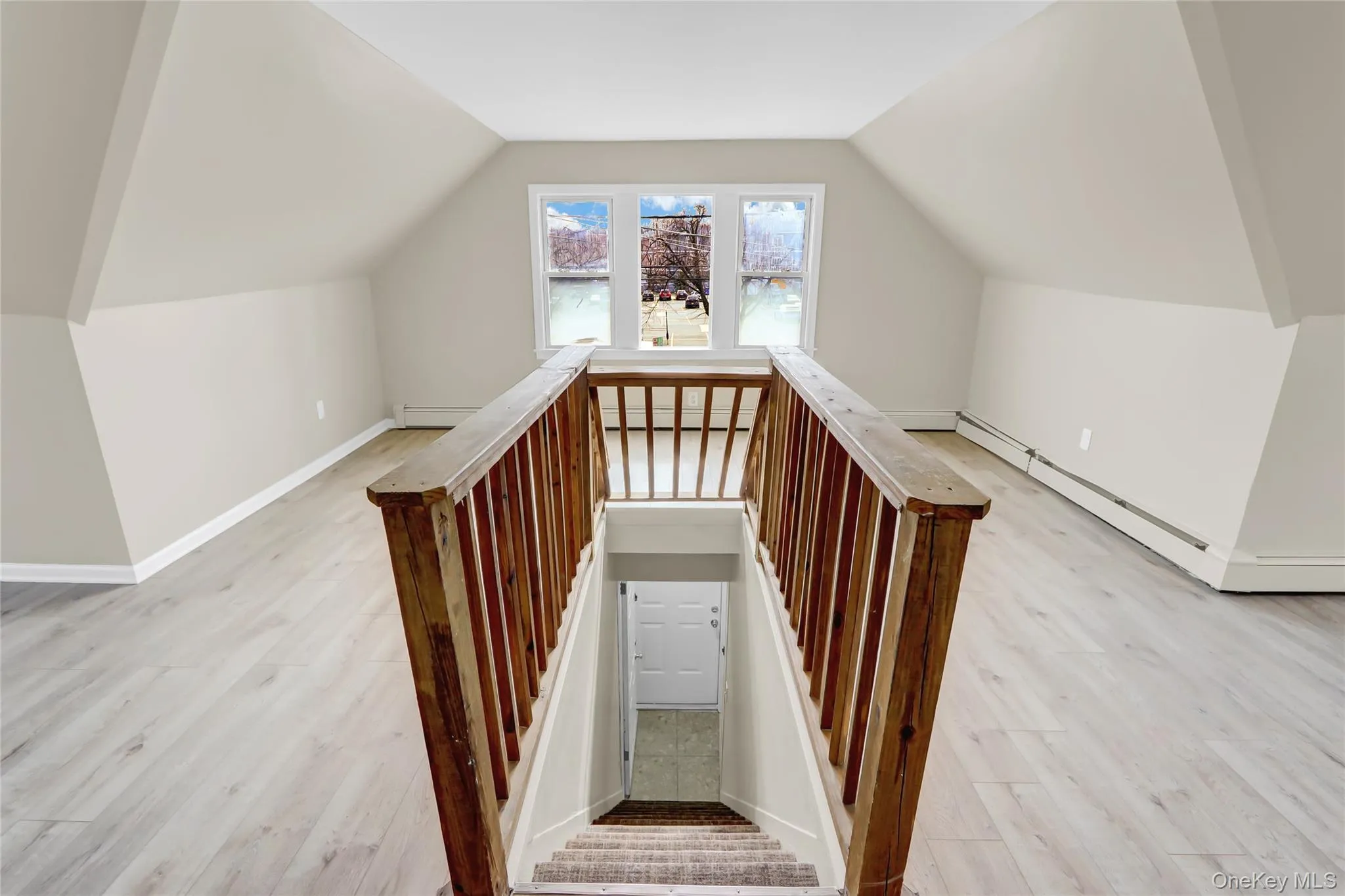 Staircase featuring a baseboard heating unit, lofted ceiling, and wood finished floors Staircase featuring a baseboard heating unit, lofted ceiling, and wood finished floors
