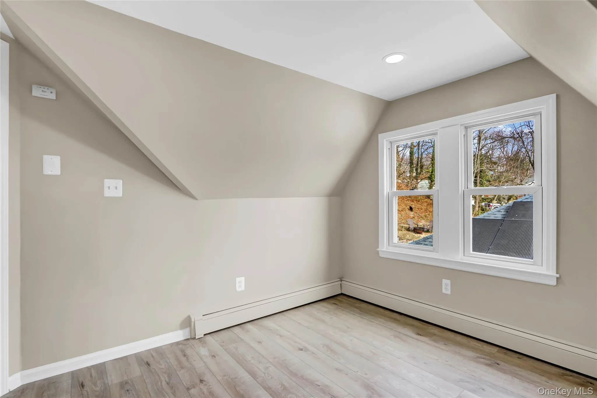 Additional living space featuring lofted ceiling, baseboards, light wood-type flooring, and a baseboard radiator Additional living space featuring lofted ceiling, baseboards, light wood-type flooring, and a baseboard radiator