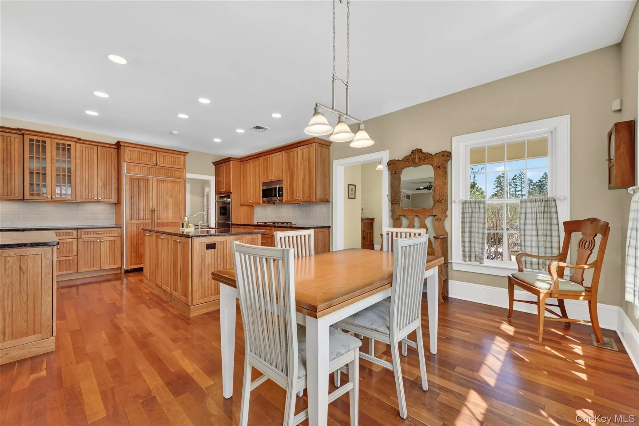 The warm and inviting eat-in kitchen with rich cabinetry and sunlit dining space, perfect for everyday meals or gathering with family and friends. Notice a separate back entrance off the kitchen for convenient unloading of the groceries! The warm and inviting eat-in kitchen with rich cabinetry and sunlit dining space, perfect for everyday meals or gathering with family and friends. Notice a separate back entrance off the kitchen for convenient unloading of the groceries!