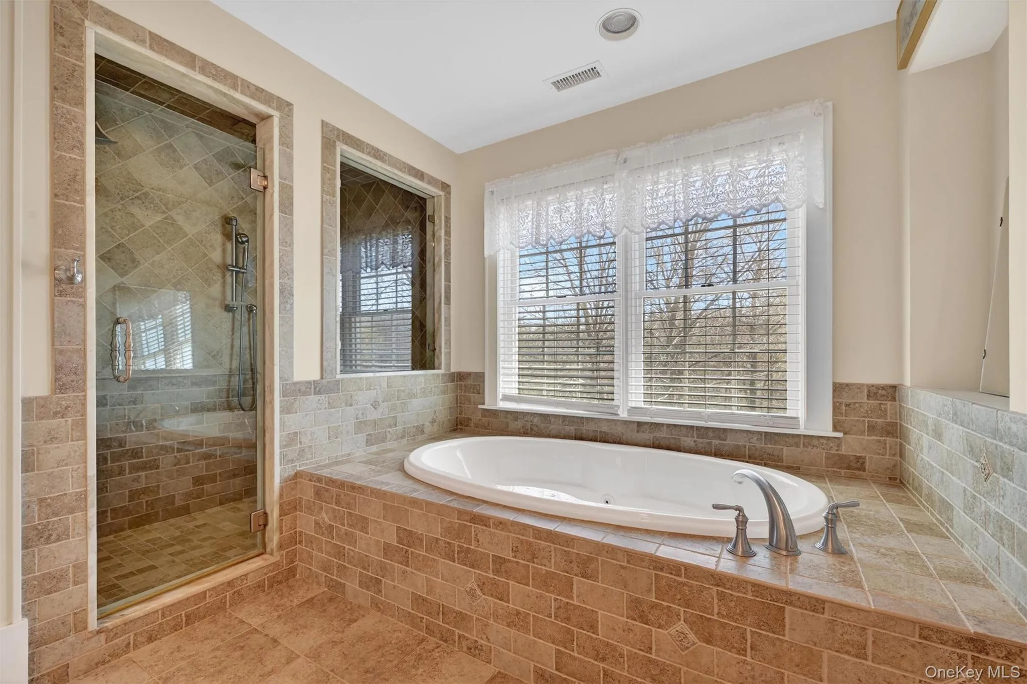 The spa-like primary bathroom offers a soaking tub set beneath large windows and a separate tiled shower, creating the perfect space to relax and recharge. The spa-like primary bathroom offers a soaking tub set beneath large windows and a separate tiled shower, creating the perfect space to relax and recharge.