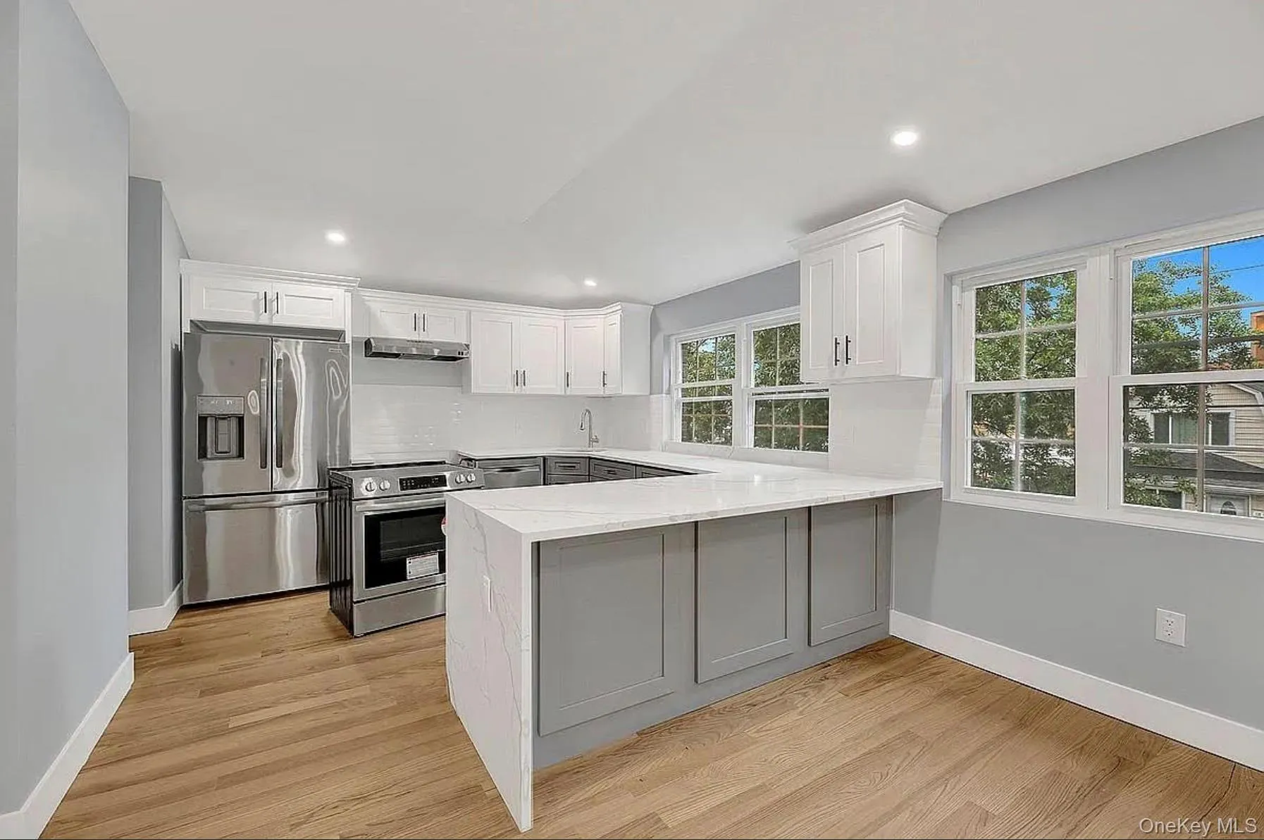 Kitchen with appliances with stainless steel finishes, under cabinet range hood, a sink, a peninsula, and baseboards Kitchen with appliances with stainless steel finishes, under cabinet range hood, a sink, a peninsula, and baseboards