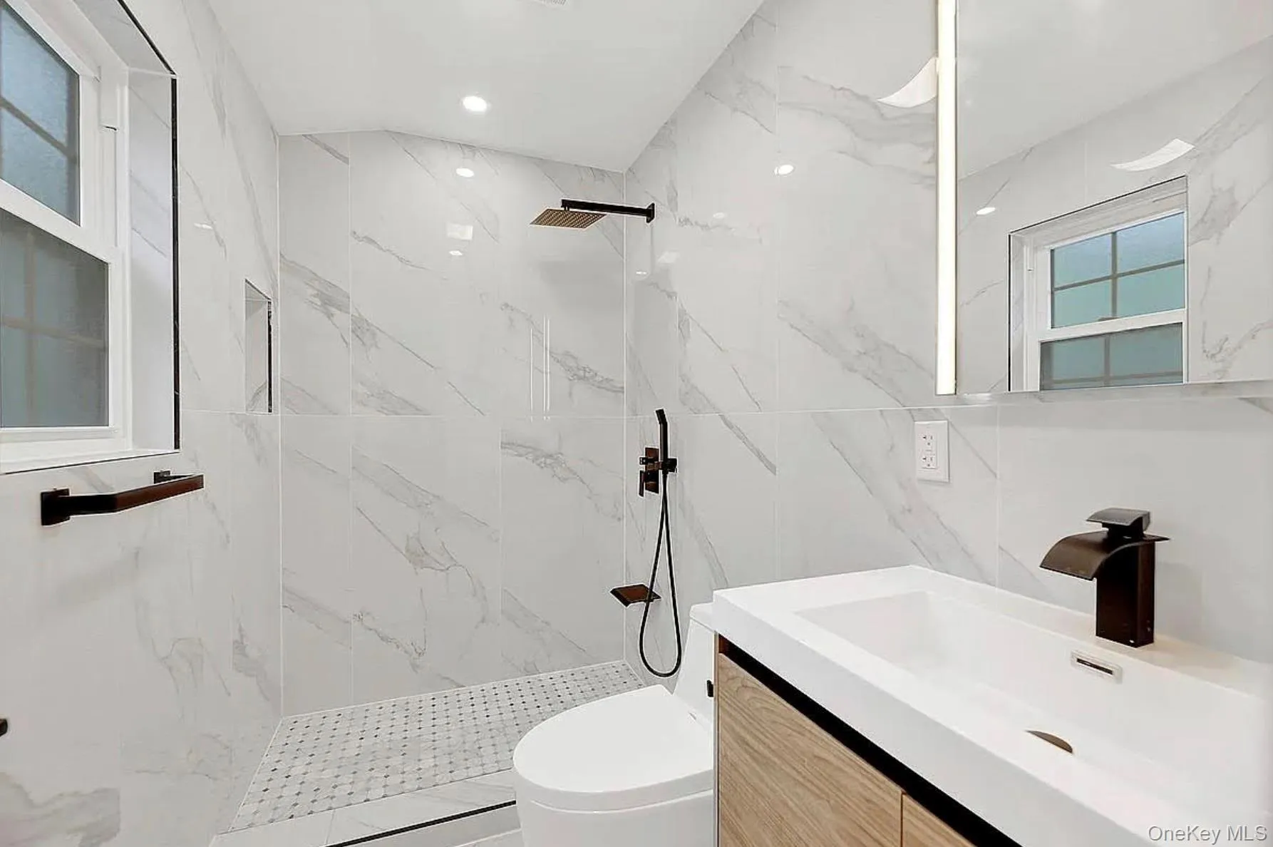 Full bathroom with toilet, a marble finish shower, vanity, and tile walls Full bathroom with toilet, a marble finish shower, vanity, and tile walls