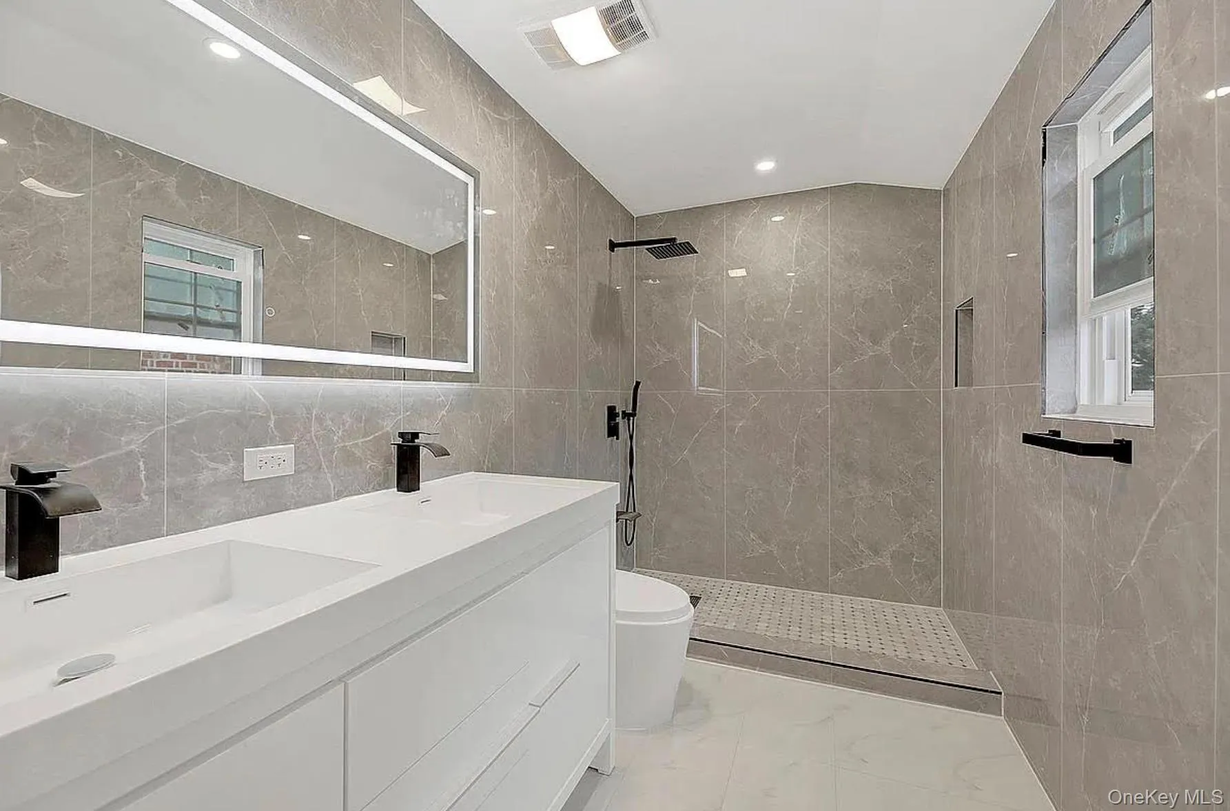 Bathroom with tile walls, walk in shower, marble finish flooring, toilet, and double vanity Bathroom with tile walls, walk in shower, marble finish flooring, toilet, and double vanity