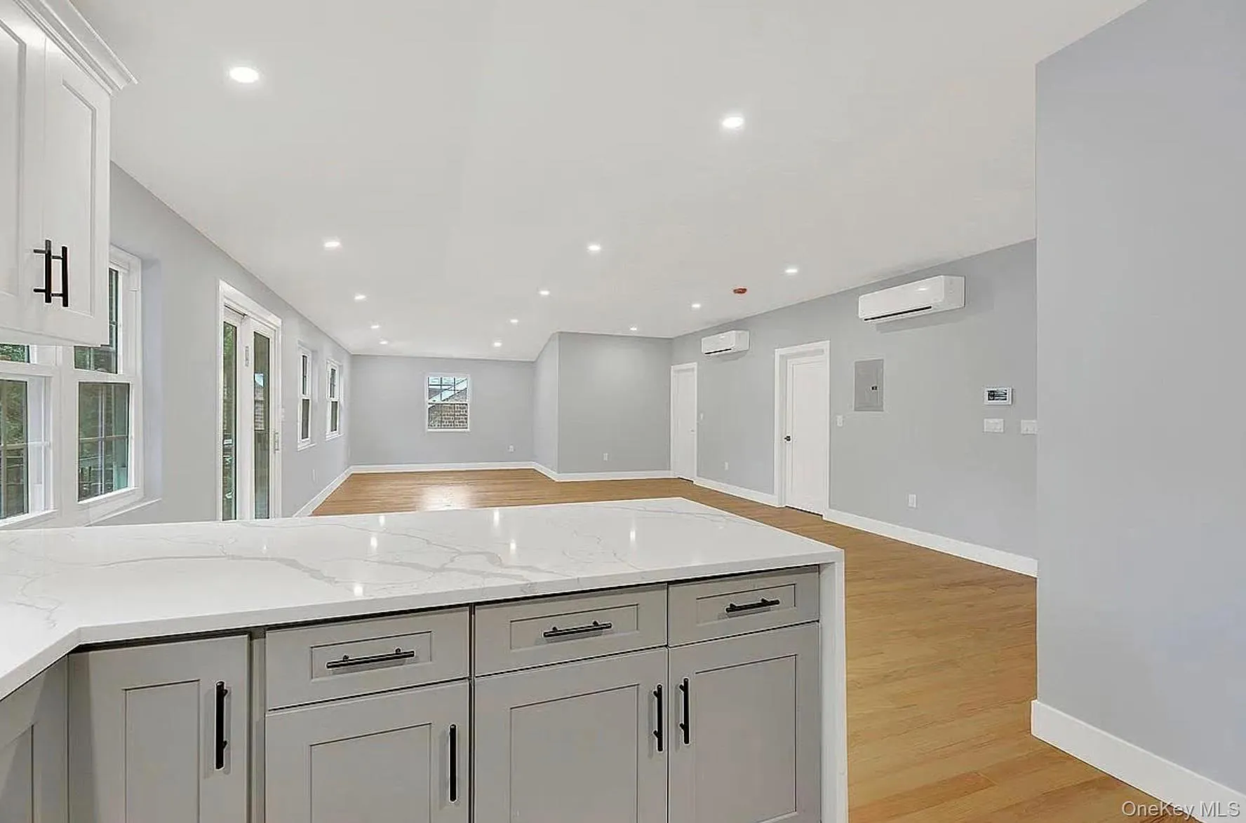 Kitchen with a wall unit AC, open floor plan, light wood-type flooring, light stone counters, and recessed lighting Kitchen with a wall unit AC, open floor plan, light wood-type flooring, light stone counters, and recessed lighting