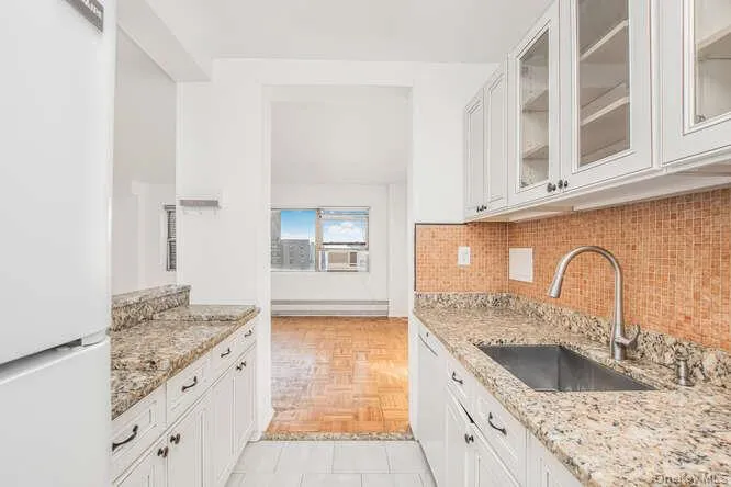 Kitchen featuring refrigerator, light stone counters, white cabinetry, and glass insert cabinets Kitchen featuring refrigerator, light stone counters, white cabinetry, and glass insert cabinets