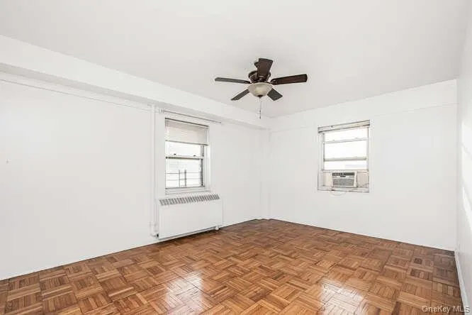 Unfurnished room featuring plenty of natural light, radiator heating unit, and ceiling fan Unfurnished room featuring plenty of natural light, radiator heating unit, and ceiling fan