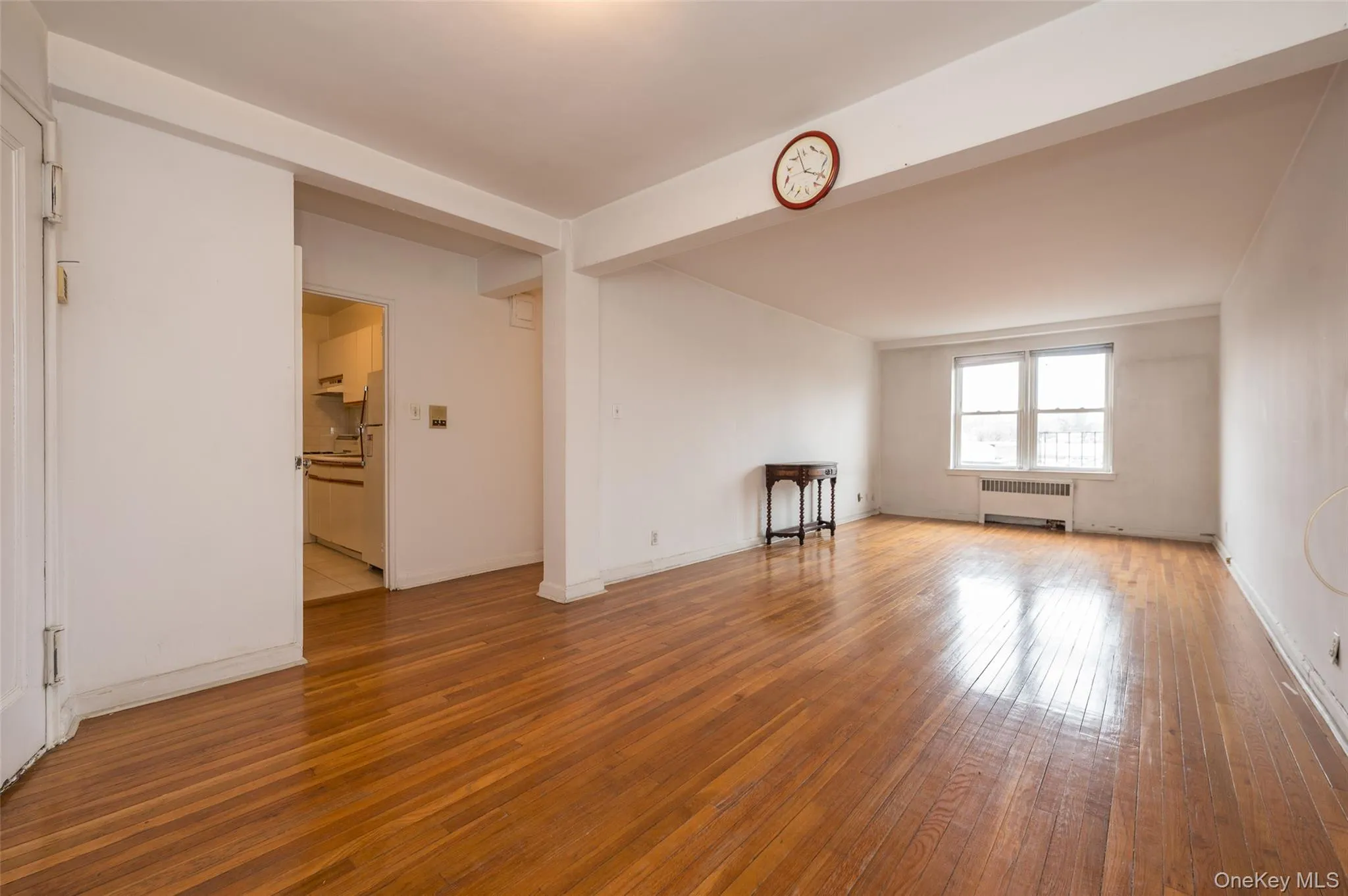 Unfurnished room with light wood-style floors, radiator, and beamed ceiling Unfurnished room with light wood-style floors, radiator, and beamed ceiling