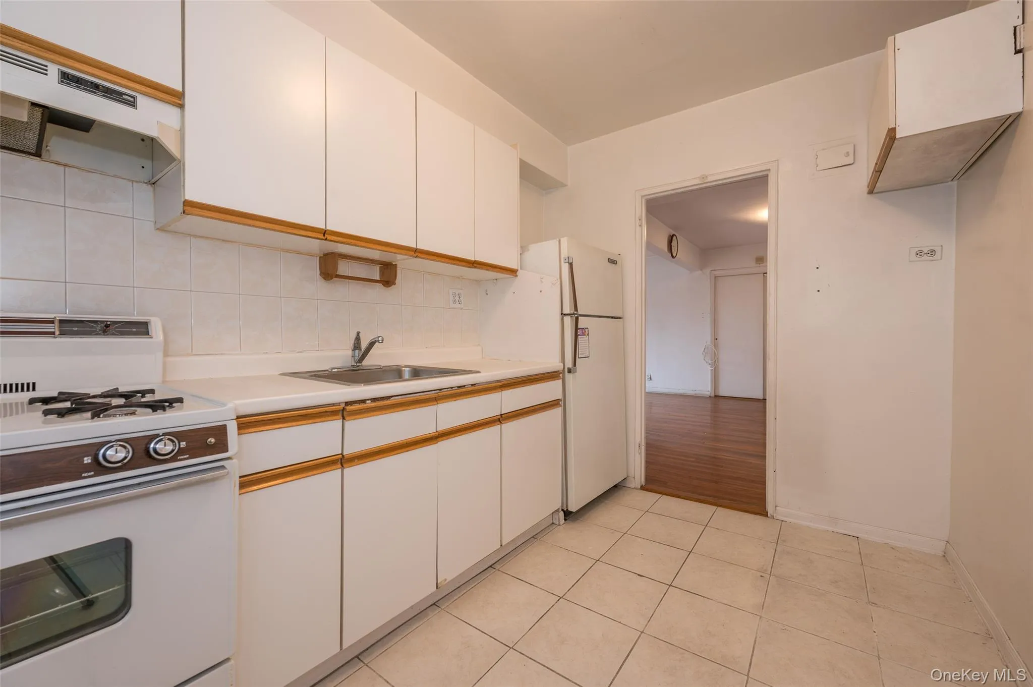Kitchen with white range with gas stovetop, light countertops, backsplash, dual tone cabinets, and light tile patterned floors Kitchen with white range with gas stovetop, light countertops, backsplash, dual tone cabinets, and light tile patterned floors