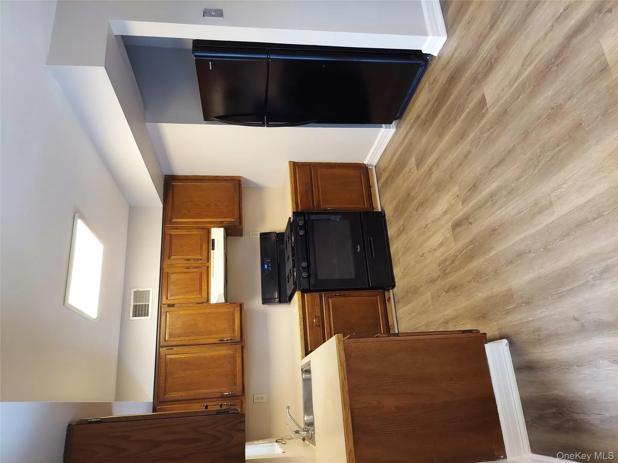 Kitchen featuring refrigerator, dishwasher, light countertops, black gas range oven, a sink, and exhaust hood Kitchen featuring refrigerator, dishwasher, light countertops, black gas range oven, a sink, and exhaust hood