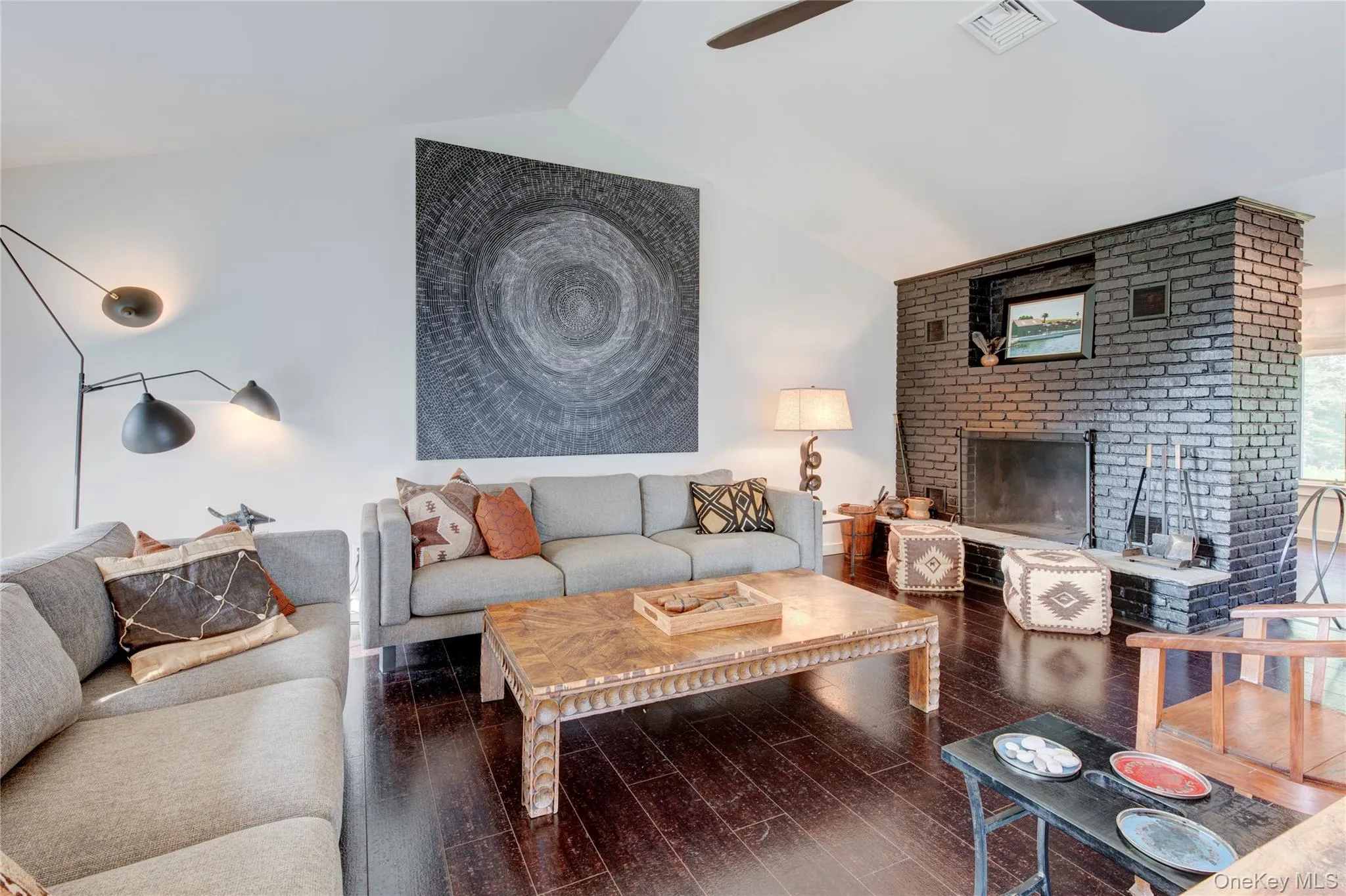 Living room featuring vaulted ceiling, hardwood / wood-style floors, ceiling fan, and a fireplace Living room featuring vaulted ceiling, hardwood / wood-style floors, ceiling fan, and a fireplace