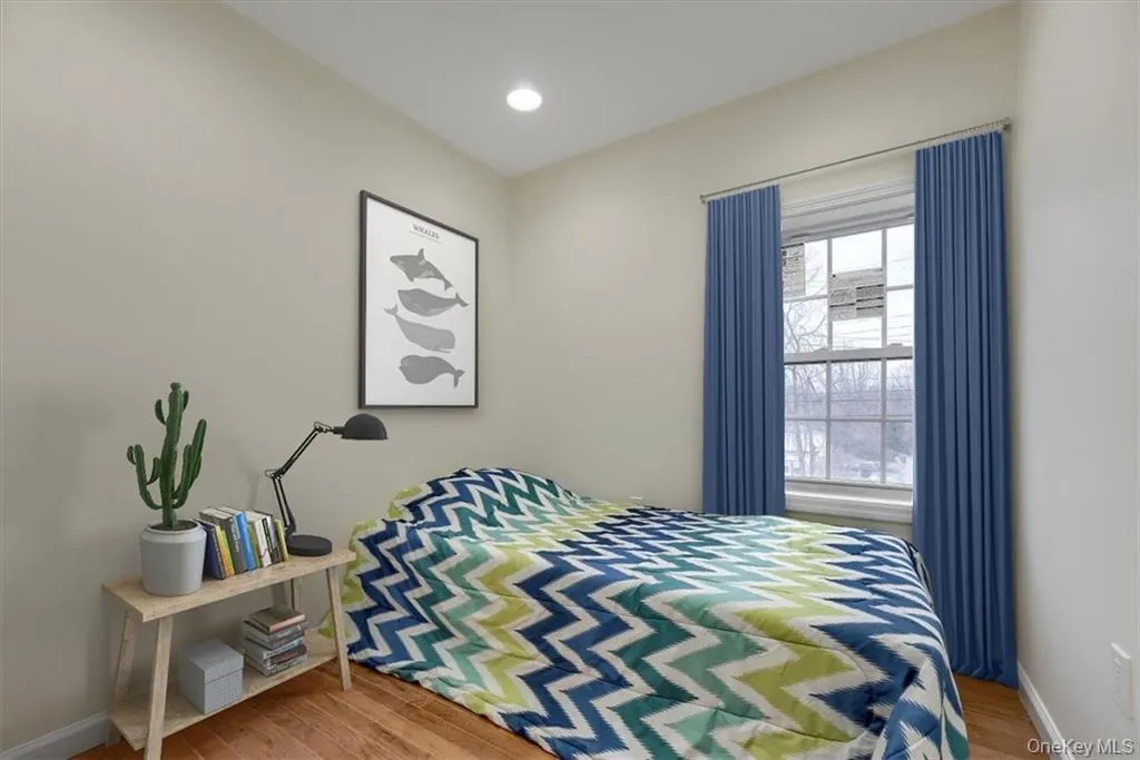 Virtually Staged, Bright bedroom featuring hardwood floors, recessed lighting, and a large window providing natural light. Virtually Staged, Bright bedroom featuring hardwood floors, recessed lighting, and a large window providing natural light.