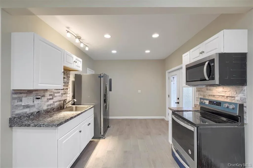Modern kitchen featuring white cabinetry, granite countertops, stainless steel appliances, and recessed lighting. Modern kitchen featuring white cabinetry, granite countertops, stainless steel appliances, and recessed lighting.