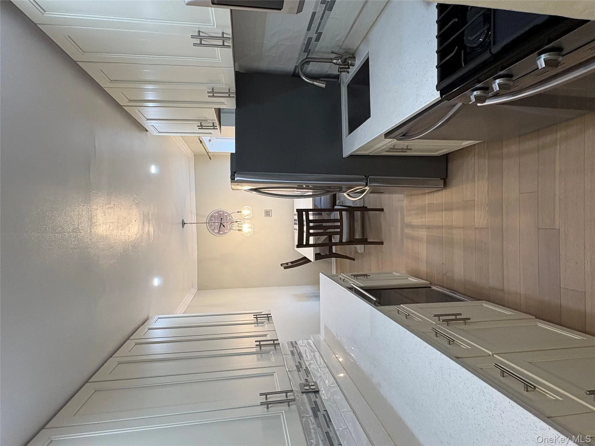 Kitchen featuring decorative backsplash, stainless steel appliances, white cabinets, ornamental molding, and light stone counters Kitchen featuring decorative backsplash, stainless steel appliances, white cabinets, ornamental molding, and light stone counters