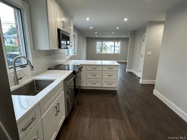 Kitchen with a peninsula, white cabinetry, dark wood finished floors, stainless steel appliances, and recessed lighting Kitchen with a peninsula, white cabinetry, dark wood finished floors, stainless steel appliances, and recessed lighting