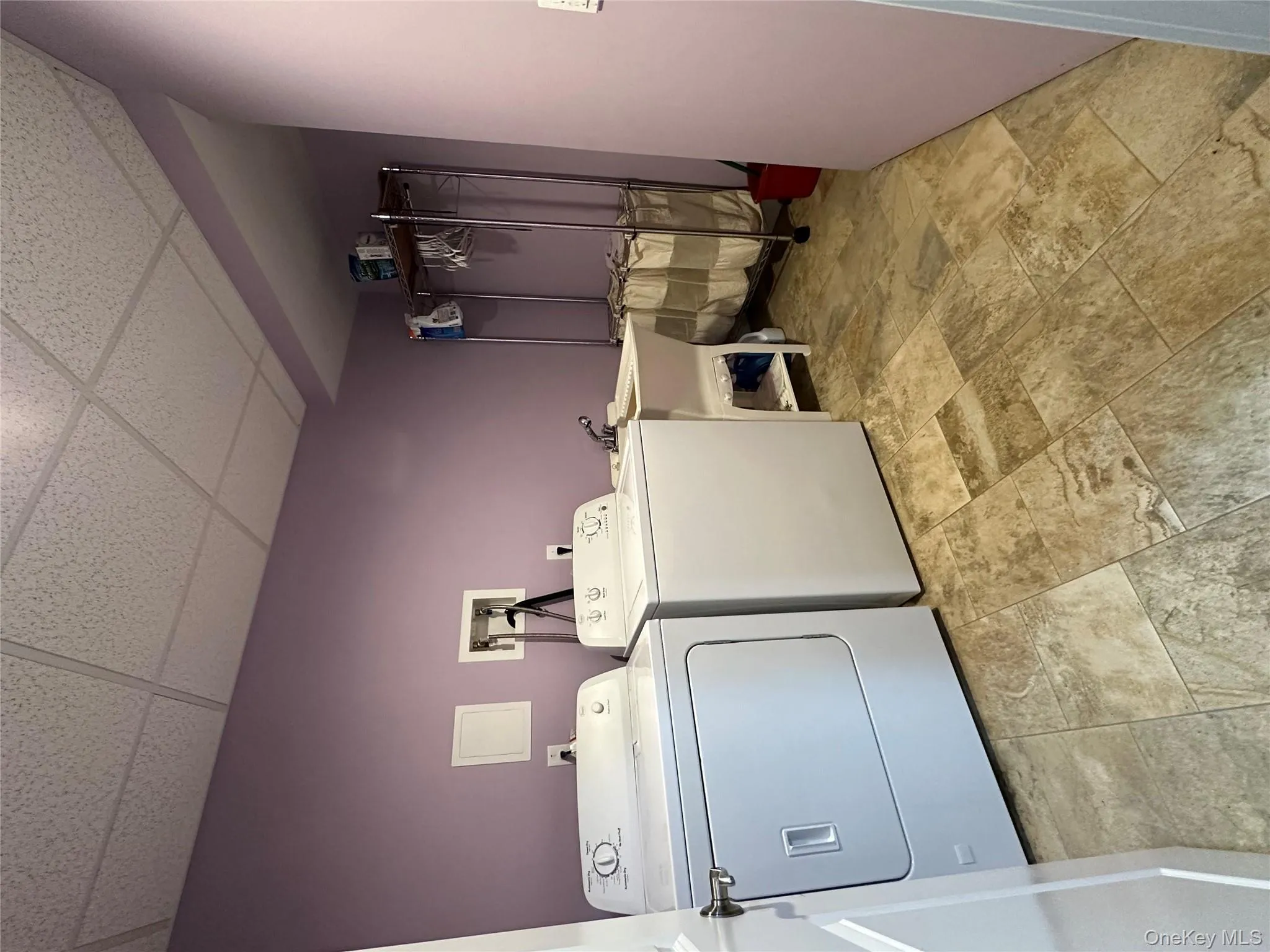 Laundry area featuring a drop ceiling, light stone finish flooring, and washer and clothes dryer Laundry area featuring a drop ceiling, light stone finish flooring, and washer and clothes dryer