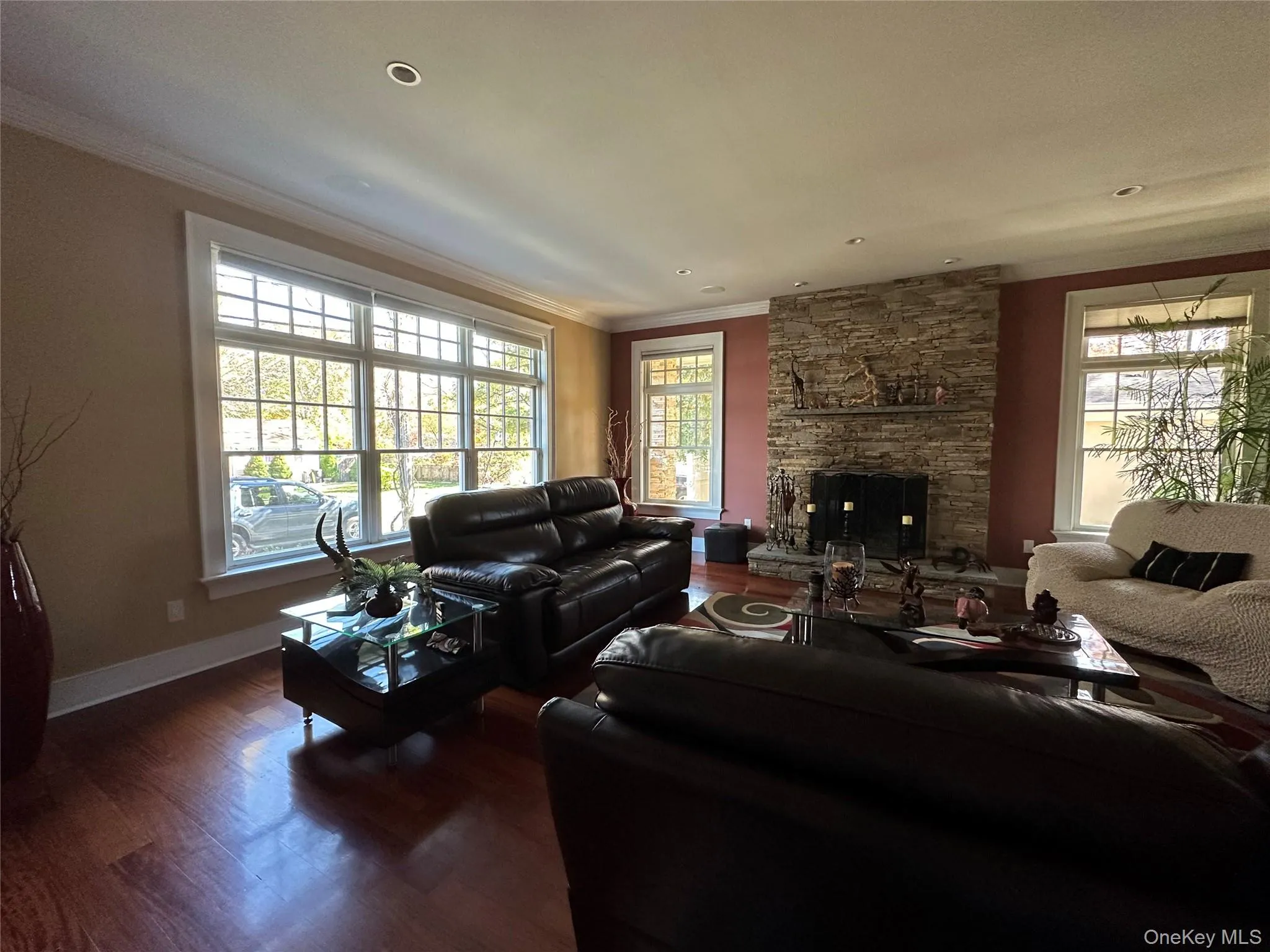 Living room featuring ornamental molding, wood finished floors, and a fireplace Living room featuring ornamental molding, wood finished floors, and a fireplace