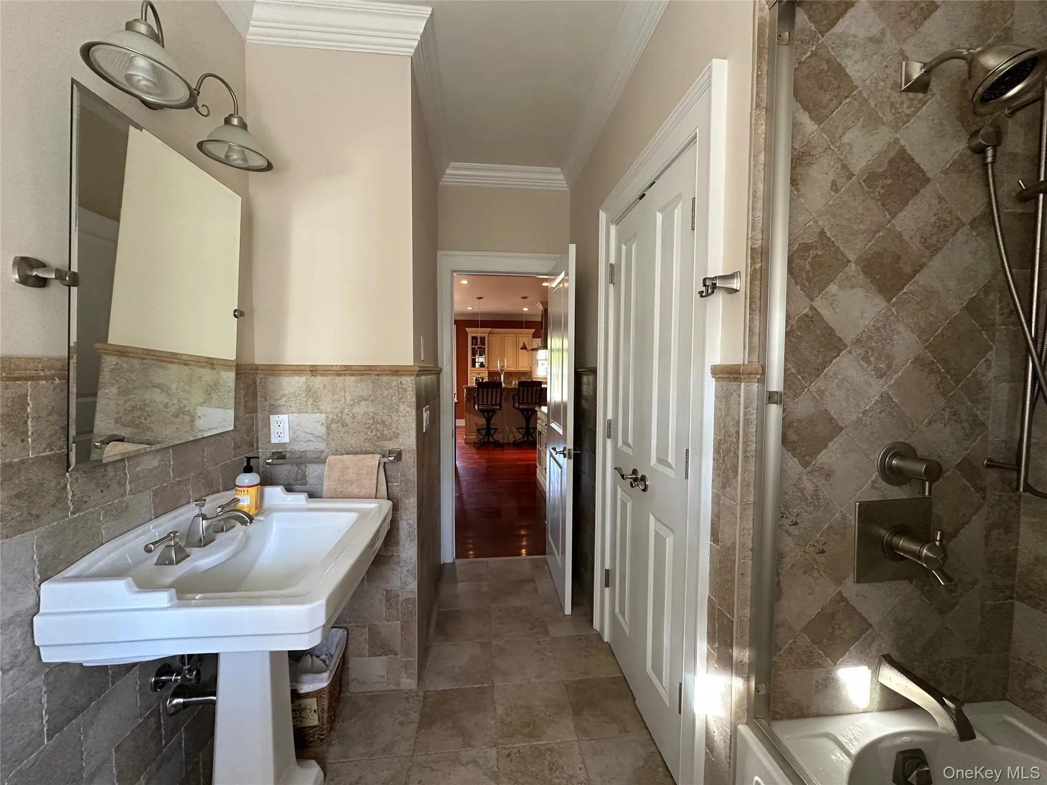 Full bath with tile walls, crown molding, a wainscoted wall, and bathing tub / shower combination Full bath with tile walls, crown molding, a wainscoted wall, and bathing tub / shower combination