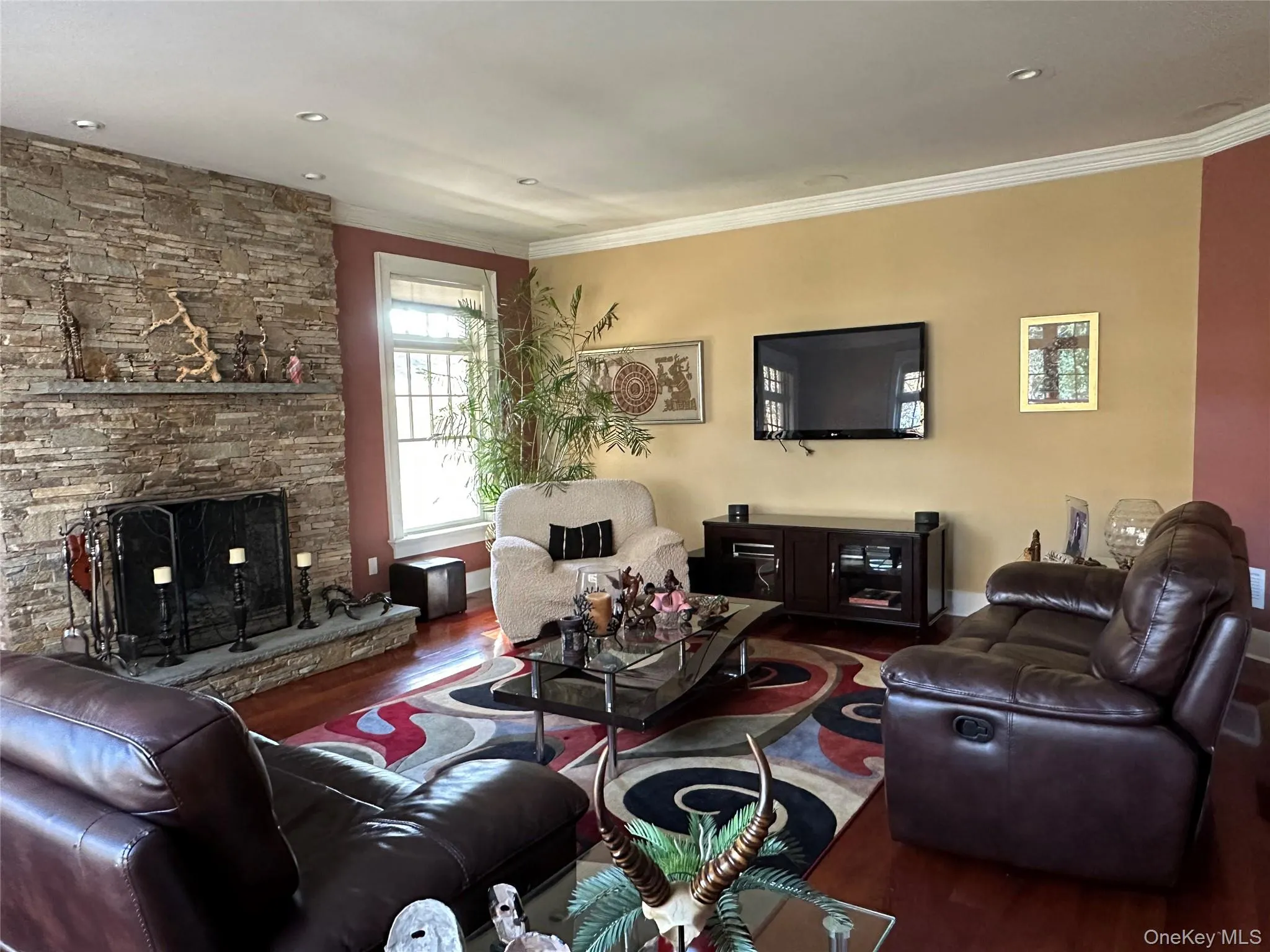 Living room featuring wood finished floors, ornamental molding, and a fireplace Living room featuring wood finished floors, ornamental molding, and a fireplace