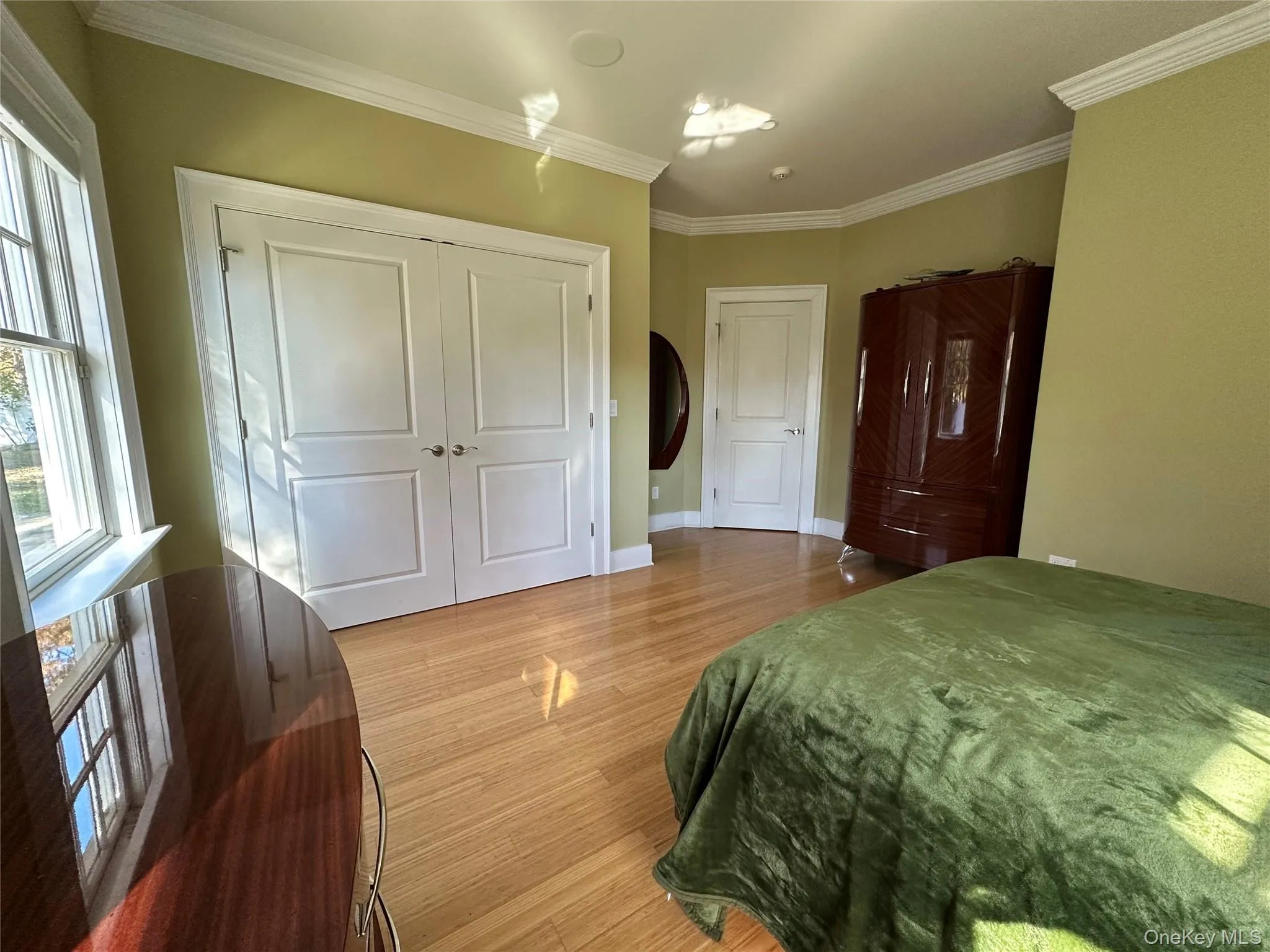 Bedroom featuring light Bamboo finished floors, ornamental molding, and an oversized closet Bedroom featuring light Bamboo finished floors, ornamental molding, and an oversized closet