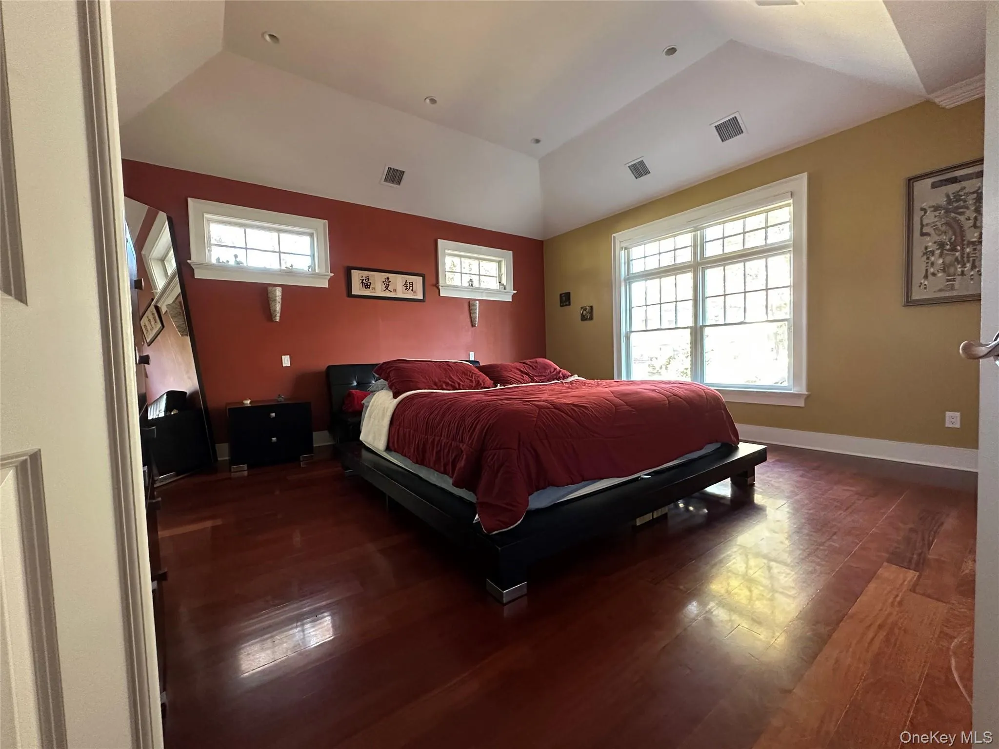 Primary bedroom with a raised ceiling and Brazilian Red Mahogony wide plank wood flooring Primary bedroom with a raised ceiling and Brazilian Red Mahogony wide plank wood flooring